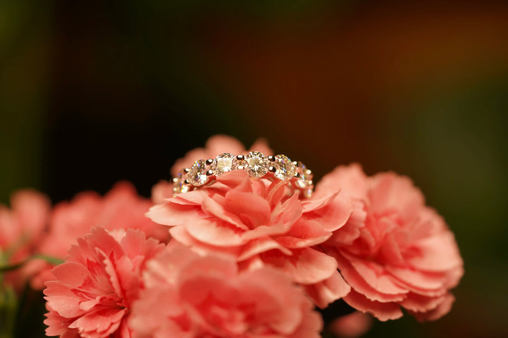 Moissanite Eternity Ring auf einer Rosa Blume im Licht funkelnd