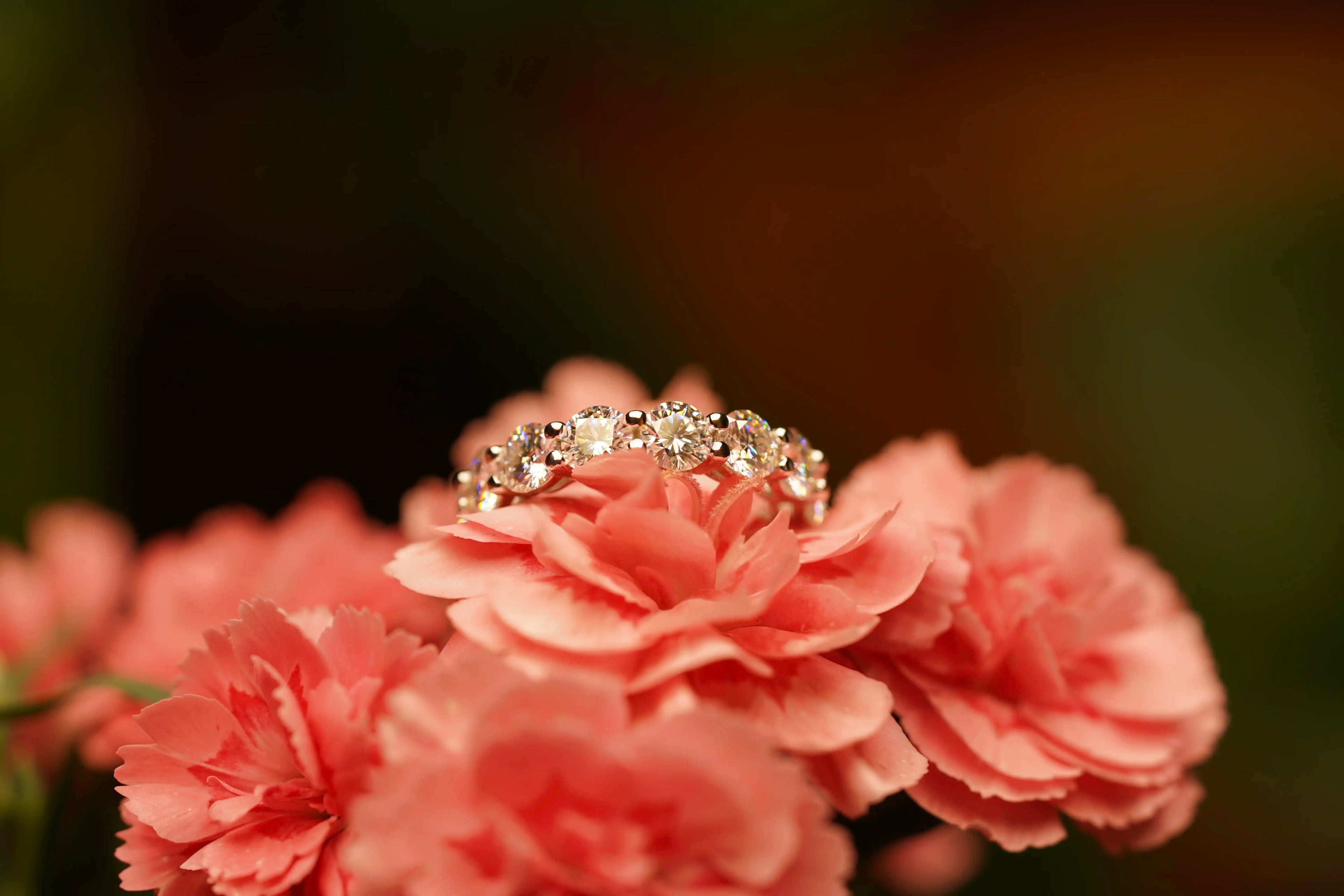 Moissanite Eternity Ring auf einer Rosa Blume im Licht funkelnd