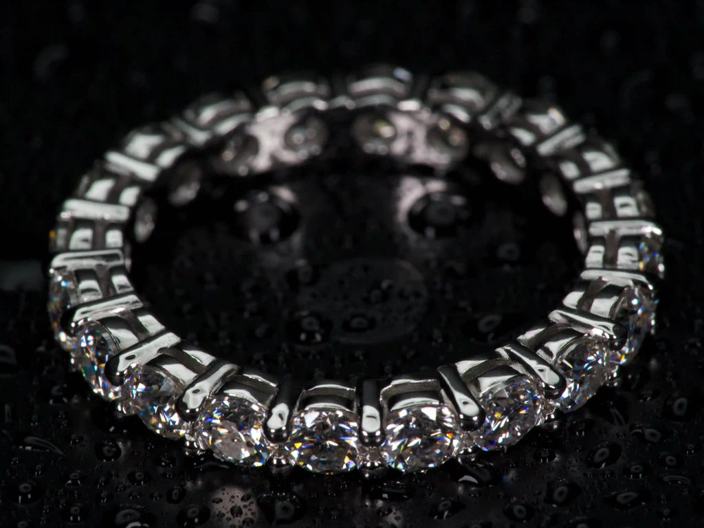 Echte Makroaufnahme eines 3mm Moissanite Eternity Rings aus 925 Silber & Weißgold im echten Licht. Rundum gefasste Moissanite mit stärkerem Funkeln als Diamanten erzeugen intensive Lichtreflexe, sichtbares Feuer und auffällige Brillanz im Alltag. Echte Fotos mit präziser Krappenfassung und hochwertiger Verarbeitung.