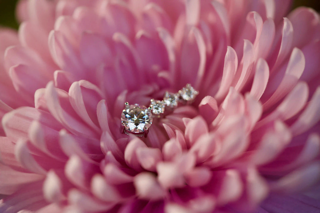 Echte Fotos von Moissanite Hängeohrringen mit frei beweglichem 1 ct Stein und drei 3 mm Moissanite Steinen im echten Licht. Stärkeres Funkeln als bei Diamanten mit intensivem Feuer bei jeder Bewegung und diamantähnlicher Härte für langlebigen Glanz im Alltag. Elegante Hängeohrringe aus 925 Silber und Weißgold als besonderes Geschenk das lange in Erinnerung bleibt.