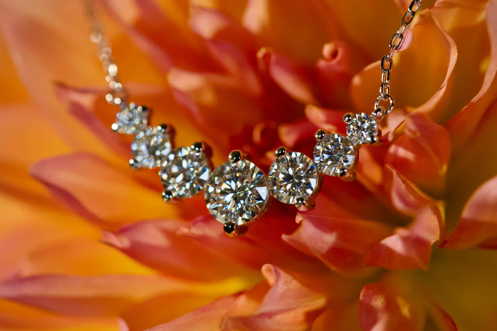 Echte Fotos einer Moissanite Kette mit Größenverlauf aus 6 Steinen im echten Licht. Stärkeres Funkeln als bei Diamanten mit intensivem Feuer und diamantähnlicher Härte für langlebigen Glanz im Alltag. Funkelnde Moissanite Kette aus 925 Silber und 18K Weißgold als elegantes Geschenk das lange in Erinnerung bleibt.