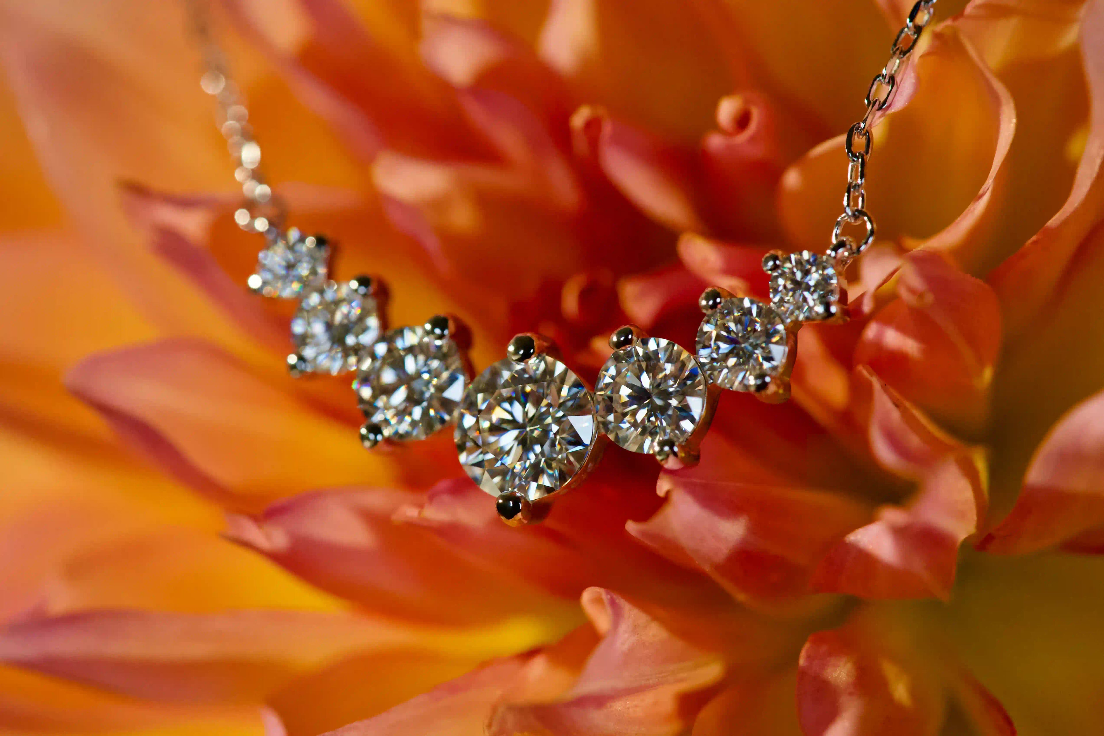 Echte Fotos einer Moissanite Kette mit Größenverlauf aus 6 Steinen im echten Licht. Stärkeres Funkeln als bei Diamanten mit intensivem Feuer und diamantähnlicher Härte für langlebigen Glanz im Alltag. Funkelnde Moissanite Kette aus 925 Silber und 18K Weißgold als elegantes Geschenk das lange in Erinnerung bleibt.