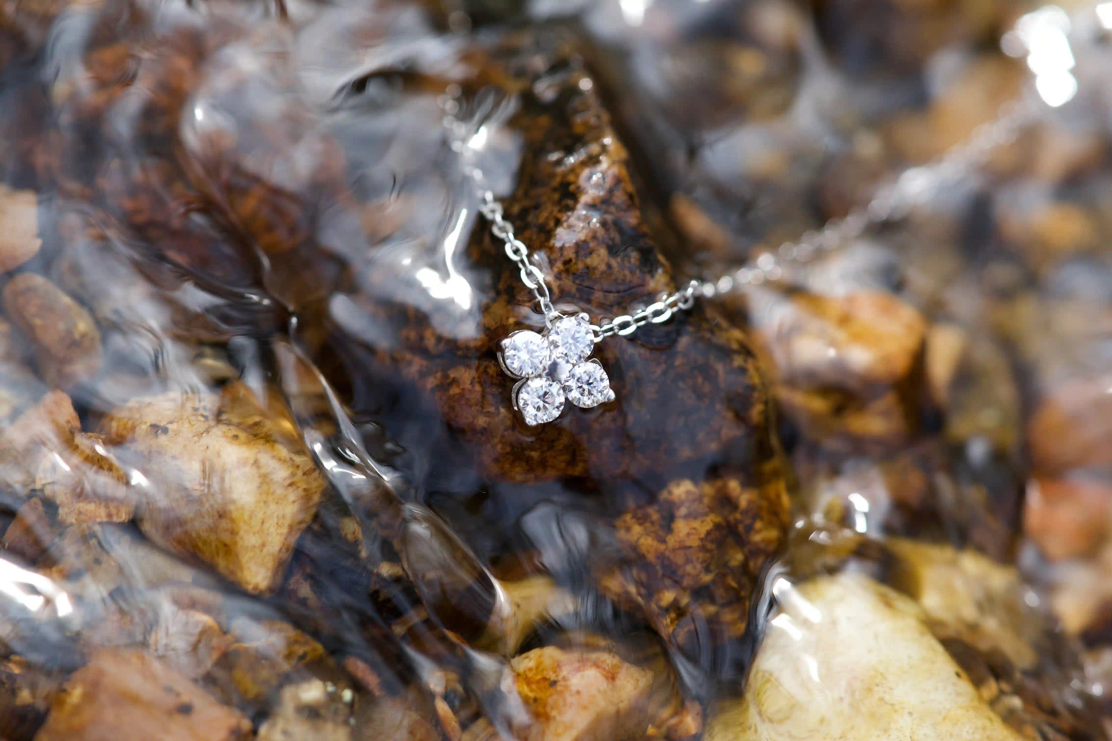 Kleeblatt Moissanit Anhänger mit 3mm Steinen unter Wasser im Bach – echtes Lichtspiel und Funkeln im Alltag ohne KI fotografiert