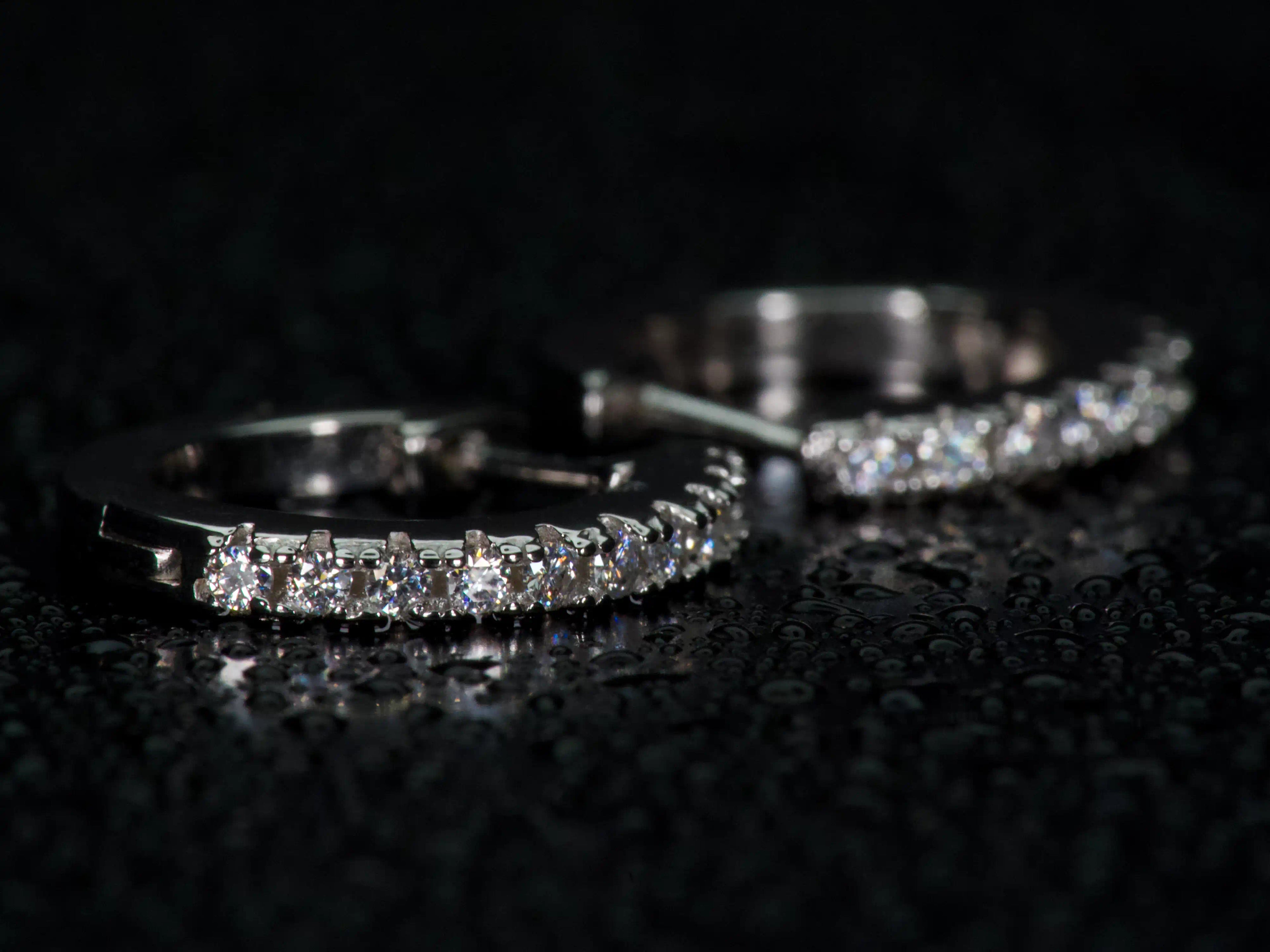 Echte Fotos von Mini Huggie Creolen im echten Licht. Seitliche Makroaufnahme mit intensivem Moissanite Feuer und stärkerem Funkeln als bei Diamanten. Diamantähnliche Härte sorgt für langlebigen Glanz im Alltag.