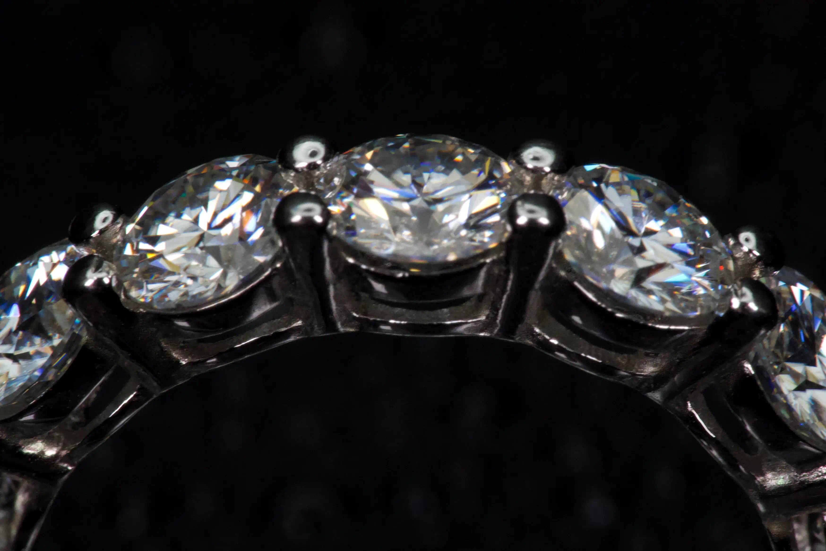 Echte Makroaufnahme: 5mm Moissanit Eternity Ring – mehrere Steine im Detail, extremes Funkeln wie Diamant, 925 Silber & Weißgold, starkes Feuer im echten Licht