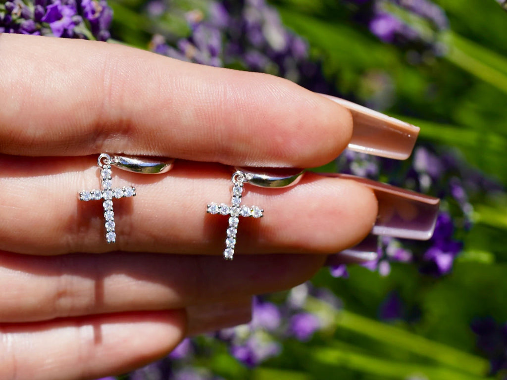 Ohrringe mit Kreuzdesign aus Moissanit auf Hand mit Lavendel im Hintergrund
