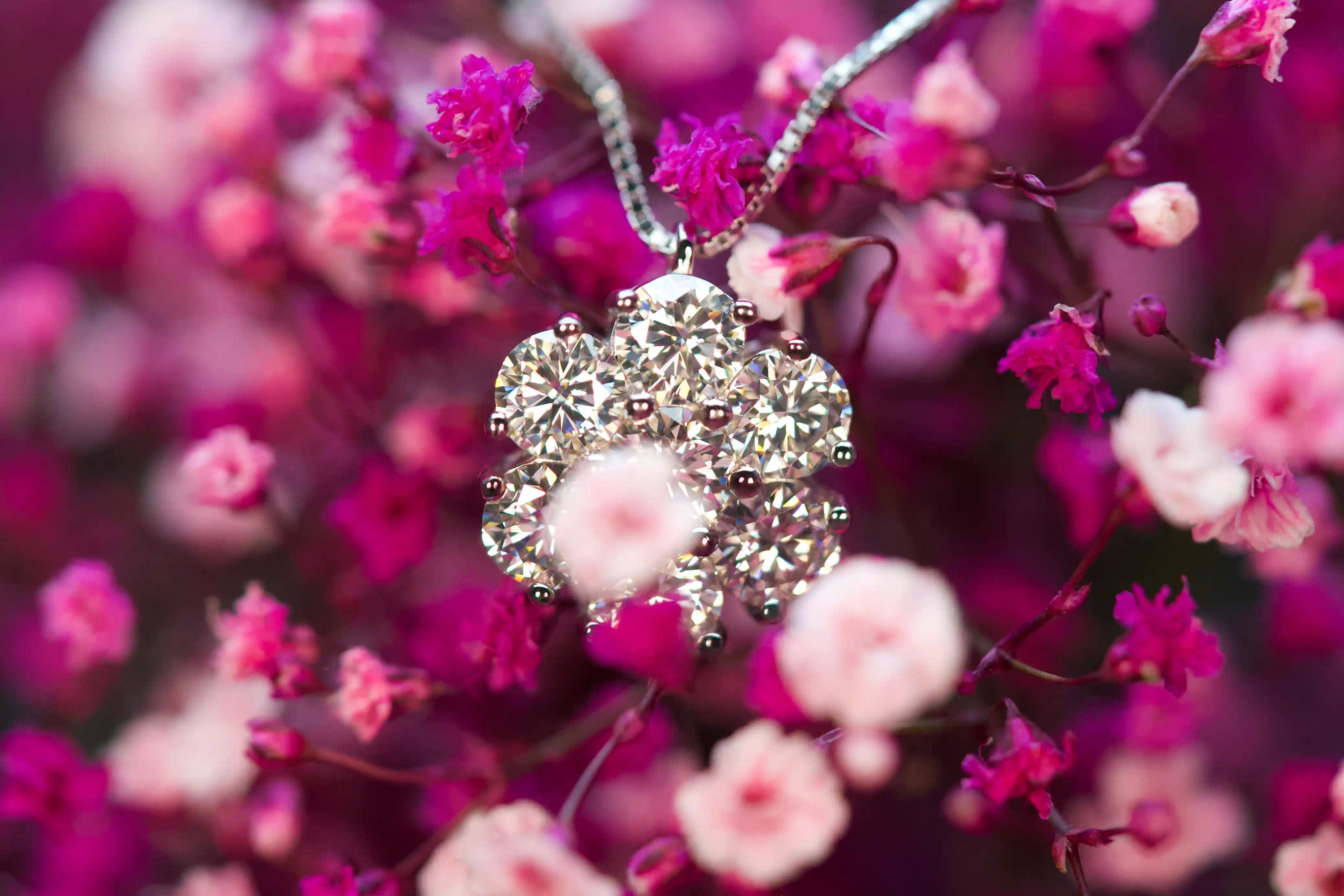 Makroaufnahme der Moissanit Kette zwischen kleinen rosa und lila Rosen. Echte Fotos zeigen starkes Funkeln, hohe Lichtbrechung und elegante Wirkung im Alltag.