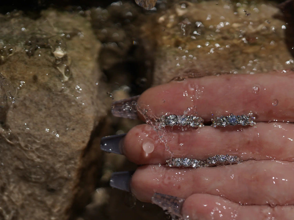 Moissanite Creolen vor Sandsteinwand – feine Mini-Creolen aus Sterling Silber mit Weißgold, klarer Rundschliff und starkes Funkeln bei jeder Bewegung.