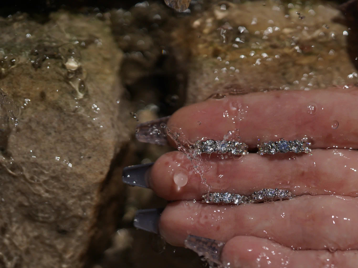 Moissanite Creolen vor Sandsteinwand – feine Mini-Creolen aus Sterling Silber mit Weißgold, klarer Rundschliff und starkes Funkeln bei jeder Bewegung.