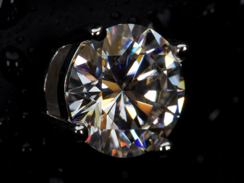 Echte Makroaufnahme eines 2ct Moissanite Brillanten mit extremem Funkeln und starkem Feuer – sichtbar intensiver als Diamant, klare Facettenstruktur, 925 Sterling Silber mit Weißgold Veredelung