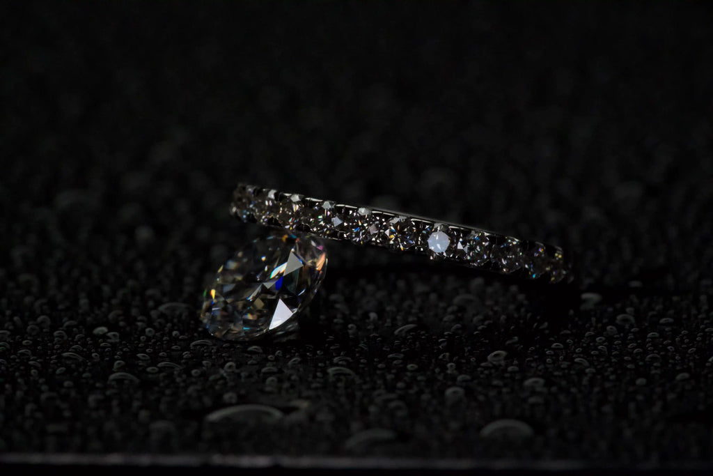 Moissanite Eternity Ring 2 mm neben einem 2 ct Moissanite Stein zum Größenvergleich, Unterschied in Größe und Funkeln klar sichtbar, echte Fotos