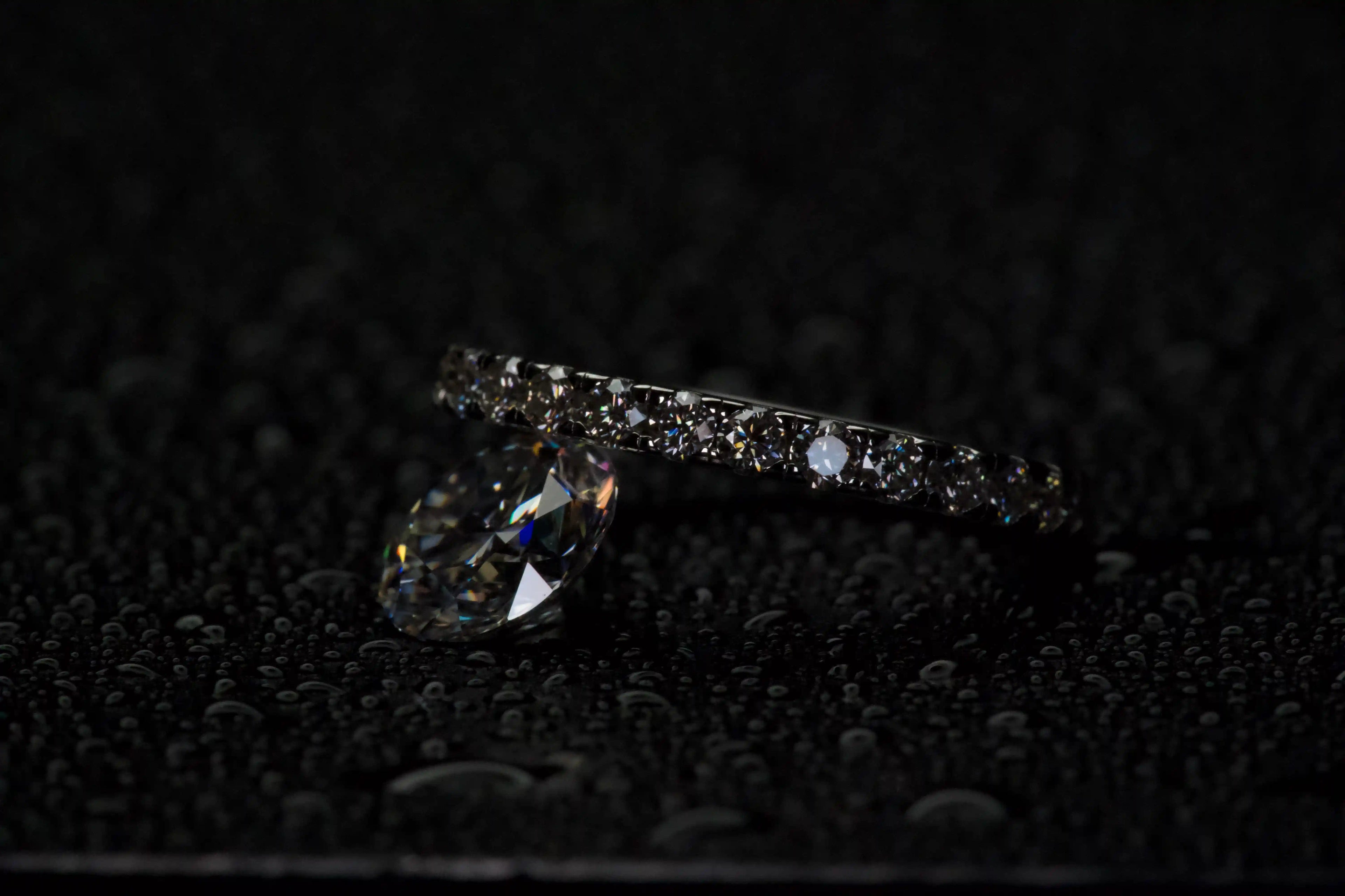 Moissanite Eternity Ring 2 mm neben einem 2 ct Moissanite Stein zum Größenvergleich, Unterschied in Größe und Funkeln klar sichtbar, echte Fotos