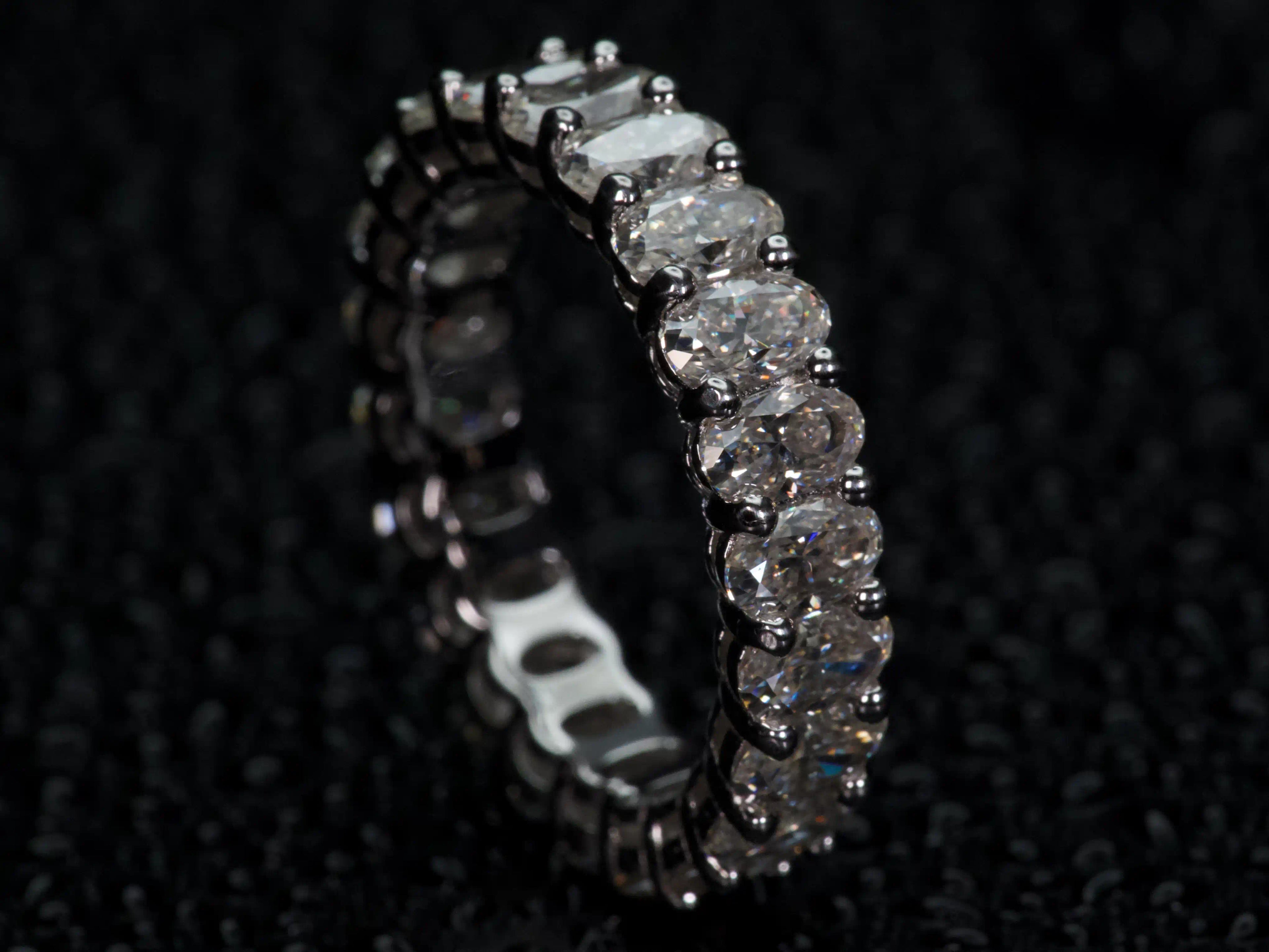 Seitliche Ansicht ovaler Moissanite Eternity Ring, starke Lichtreflexe und Funkeln bei Bewegung, echte Aufnahme ohne KI