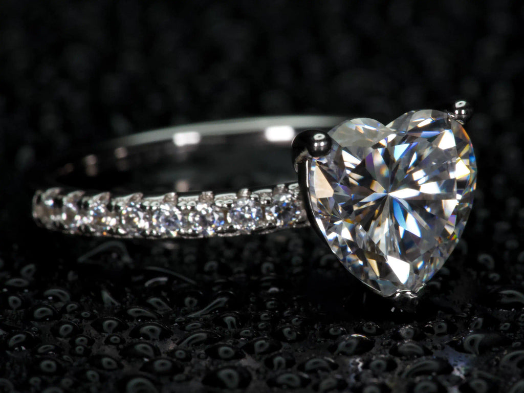 Moissanite Herz Ring 2ct von der Seite fotografiert, sichtbare Fassung und starkes Lichtspiel bei Bewegung, echtes Funkeln im realen Licht