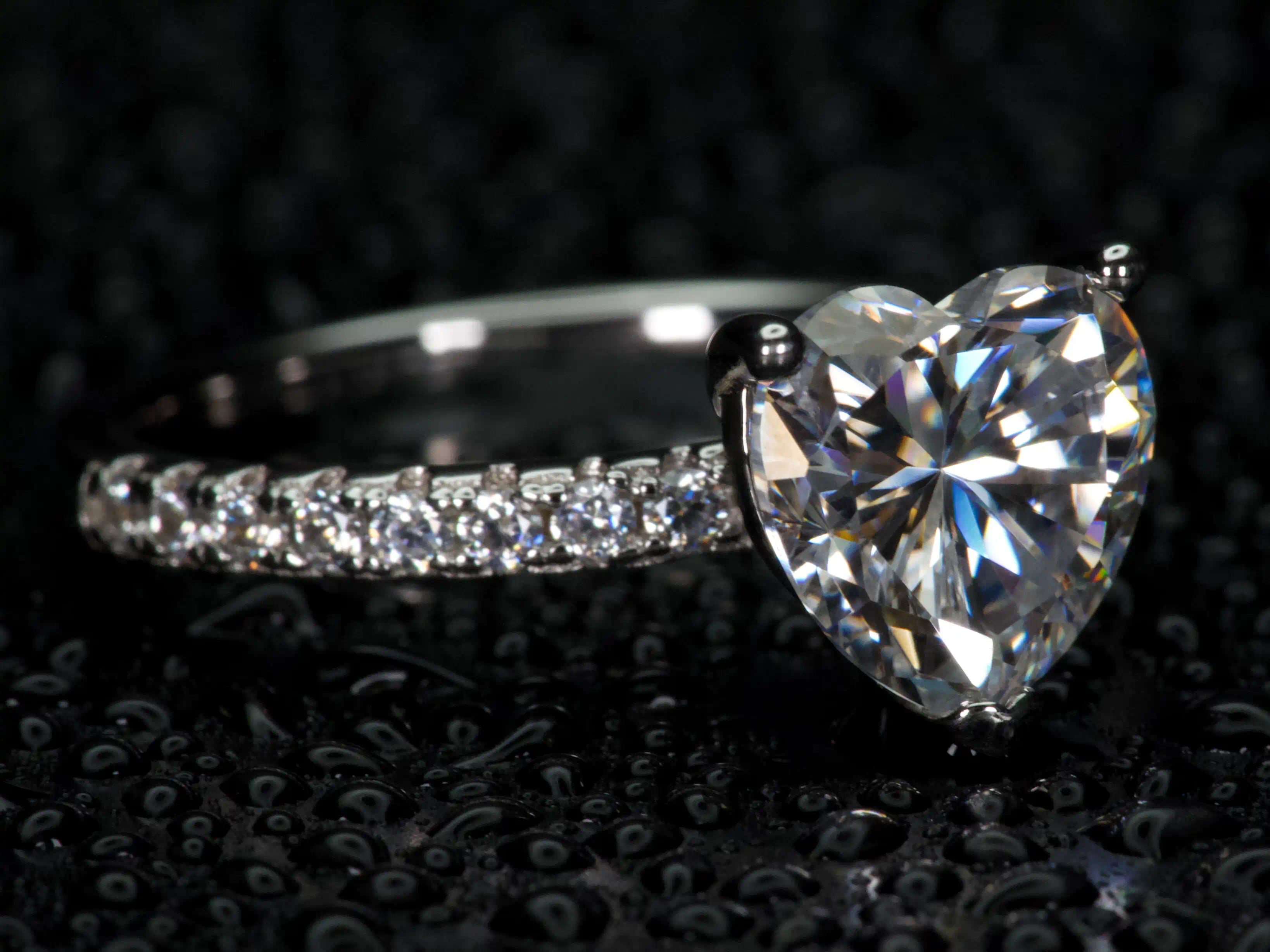 Moissanite Herz Ring 2ct von der Seite fotografiert, sichtbare Fassung und starkes Lichtspiel bei Bewegung, echtes Funkeln im realen Licht