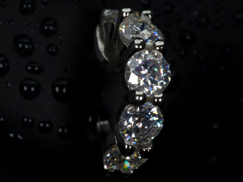 Moissanite Huggie Creolen seitlich im Halter – gleichmäßige Reihe aus 3mm Steinen, intensives Funkeln bei Bewegung, sichtbar im echten Licht, 925 Silber & Weißgold