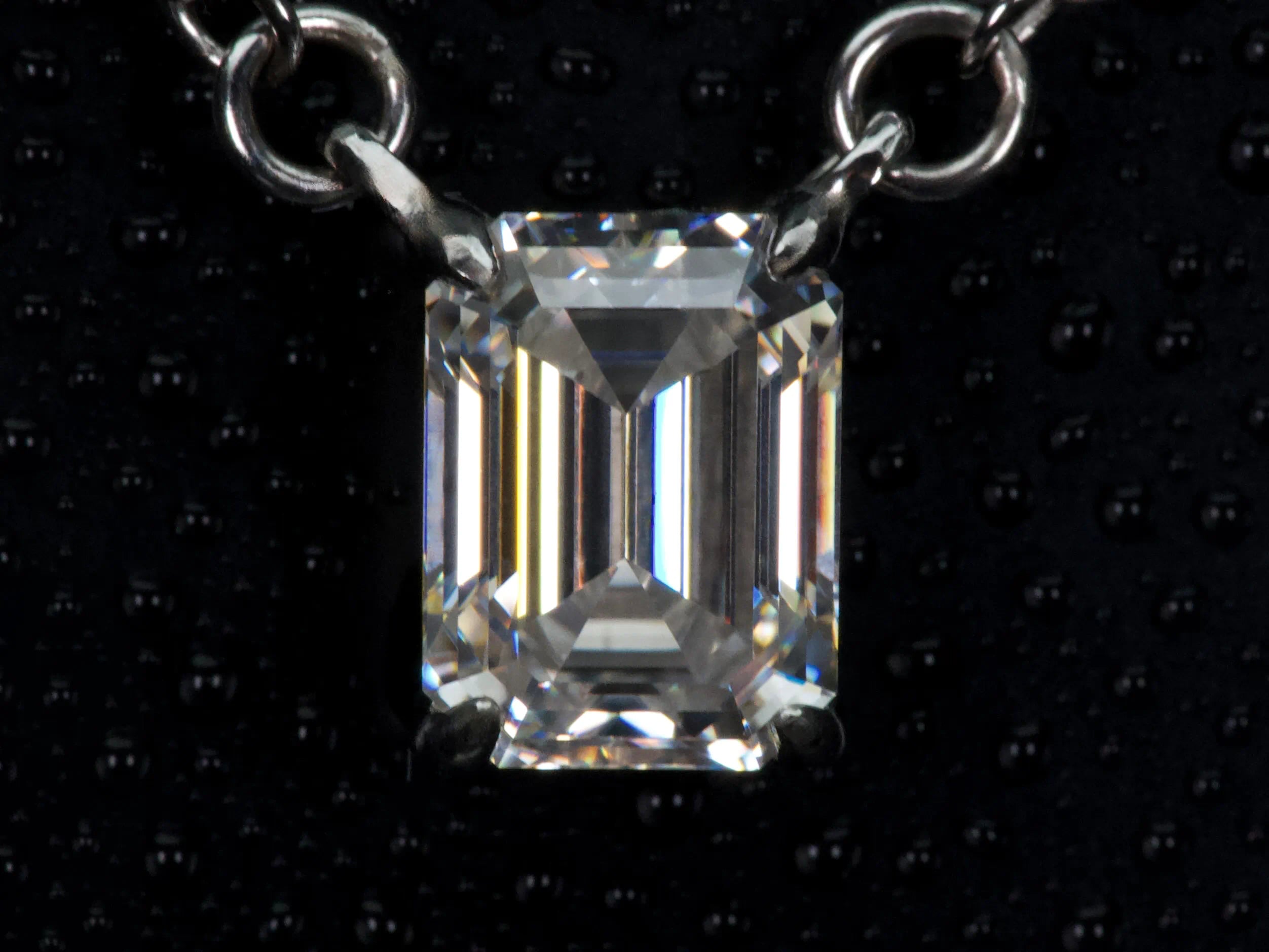 Echte Makroaufnahme einer Moissanite Kette mit 2ct Smaragdschliff Anhänger im Emerald Cut – klare Facettenlinien und spiegelnde Lichtreflexion statt Funkelstreuung, gefasst in 925 Sterling Silber mit 18K Weißgold Veredelung