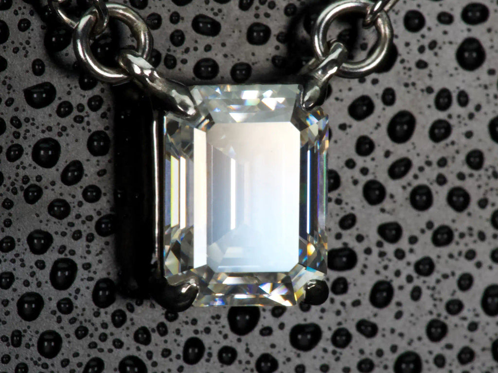Echte Makroaufnahme einer Moissanite Kette im Smaragdschliff (Emerald Cut) in Seitenansicht – große spiegelnde Lichtfläche und klare Tiefenwirkung statt starkem Funkeln, gefasst in 925 Sterling Silber mit Weißgold Veredelung