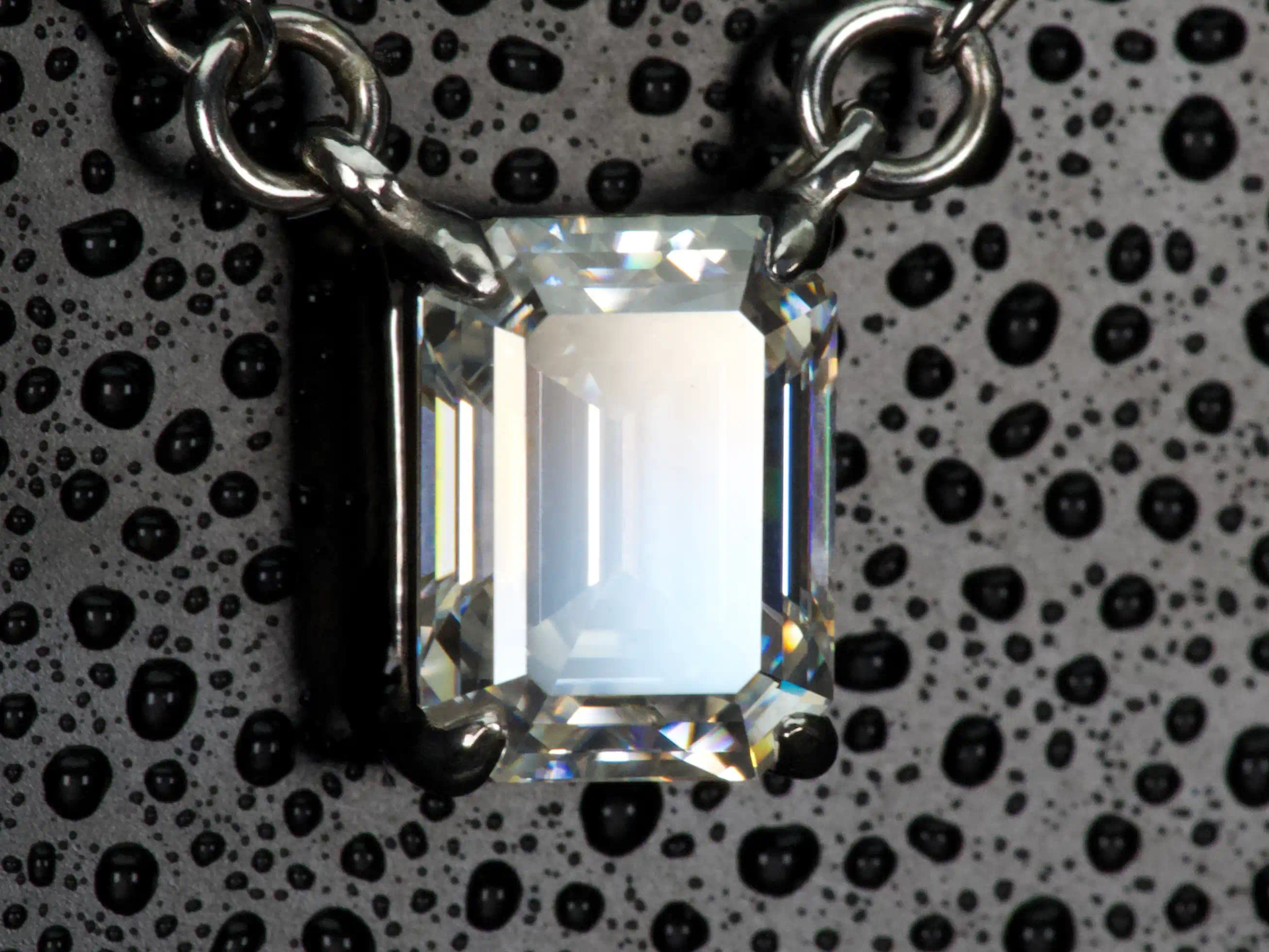 Echte Makroaufnahme einer Moissanite Kette im Smaragdschliff (Emerald Cut) in Seitenansicht – große spiegelnde Lichtfläche und klare Tiefenwirkung statt starkem Funkeln, gefasst in 925 Sterling Silber mit Weißgold Veredelung