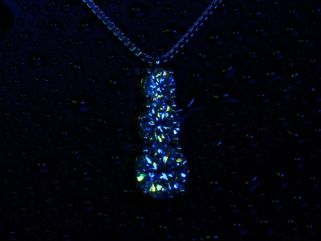 Funkelnde Moissanite Kette mit 3 Steinen in verschiedenen Größen in blau und grünem Licht 
