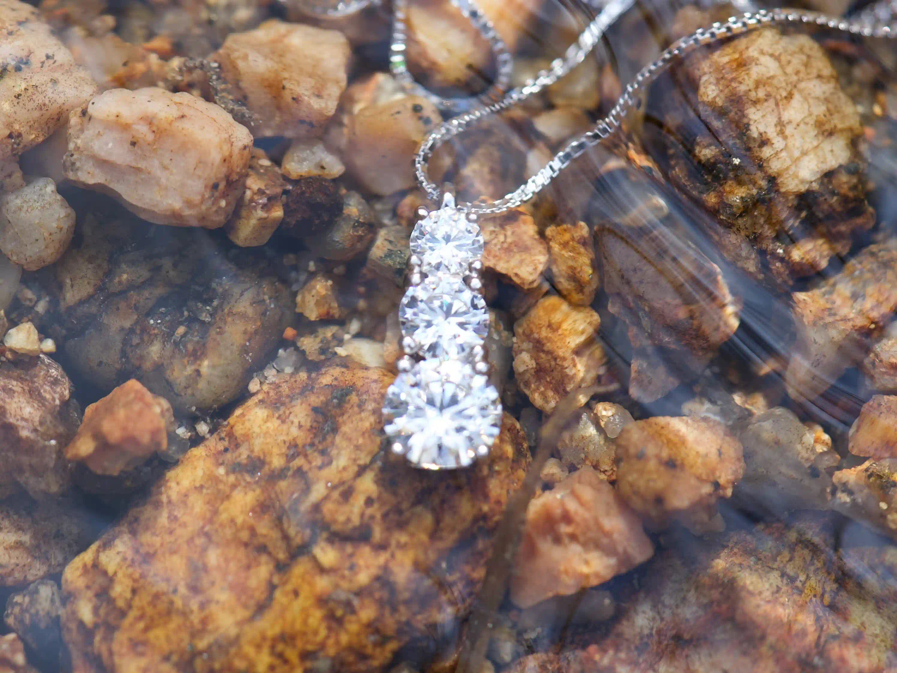 Moissanite Kette mit drei Steinen im Größenverlauf unter Wasser – echte Fotos zeigen intensives Funkeln im natürlichen Licht, feiner Übergang der Stein Größen, 925 Silber mit Weißgold Veredelung