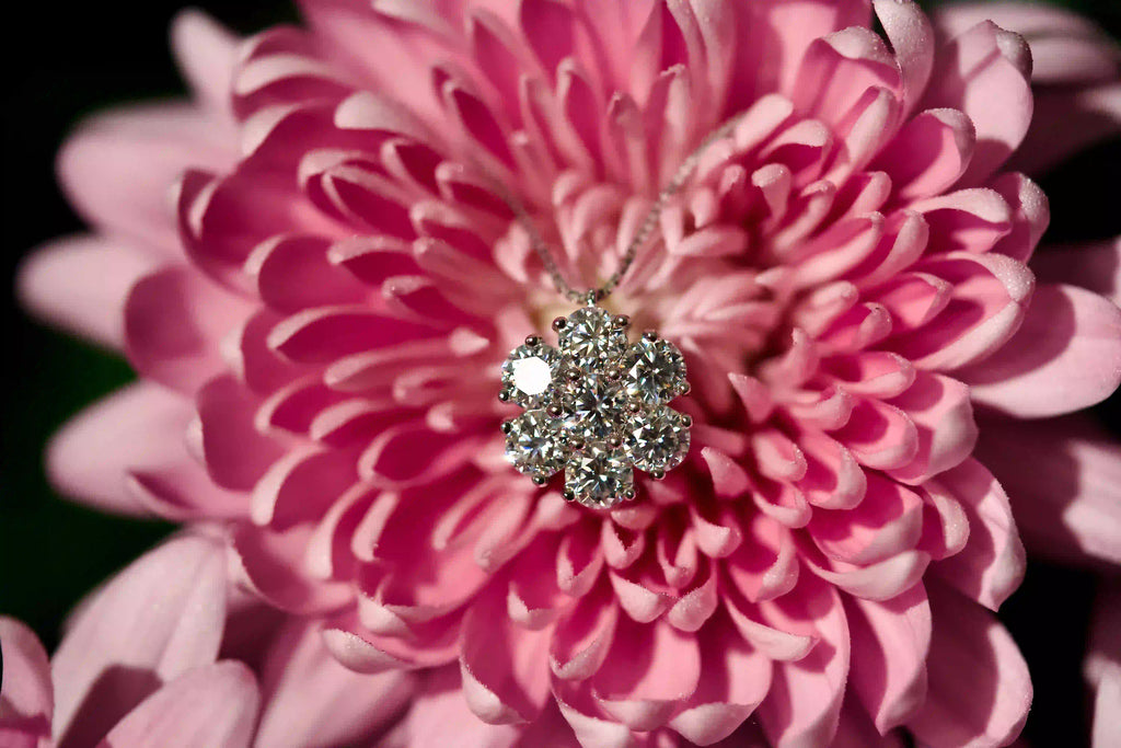 Echte Makroaufnahme einer Moissanite Kette mit Cluster Anhänger aus Brillantschliff Moissaniten auf rosa Blume