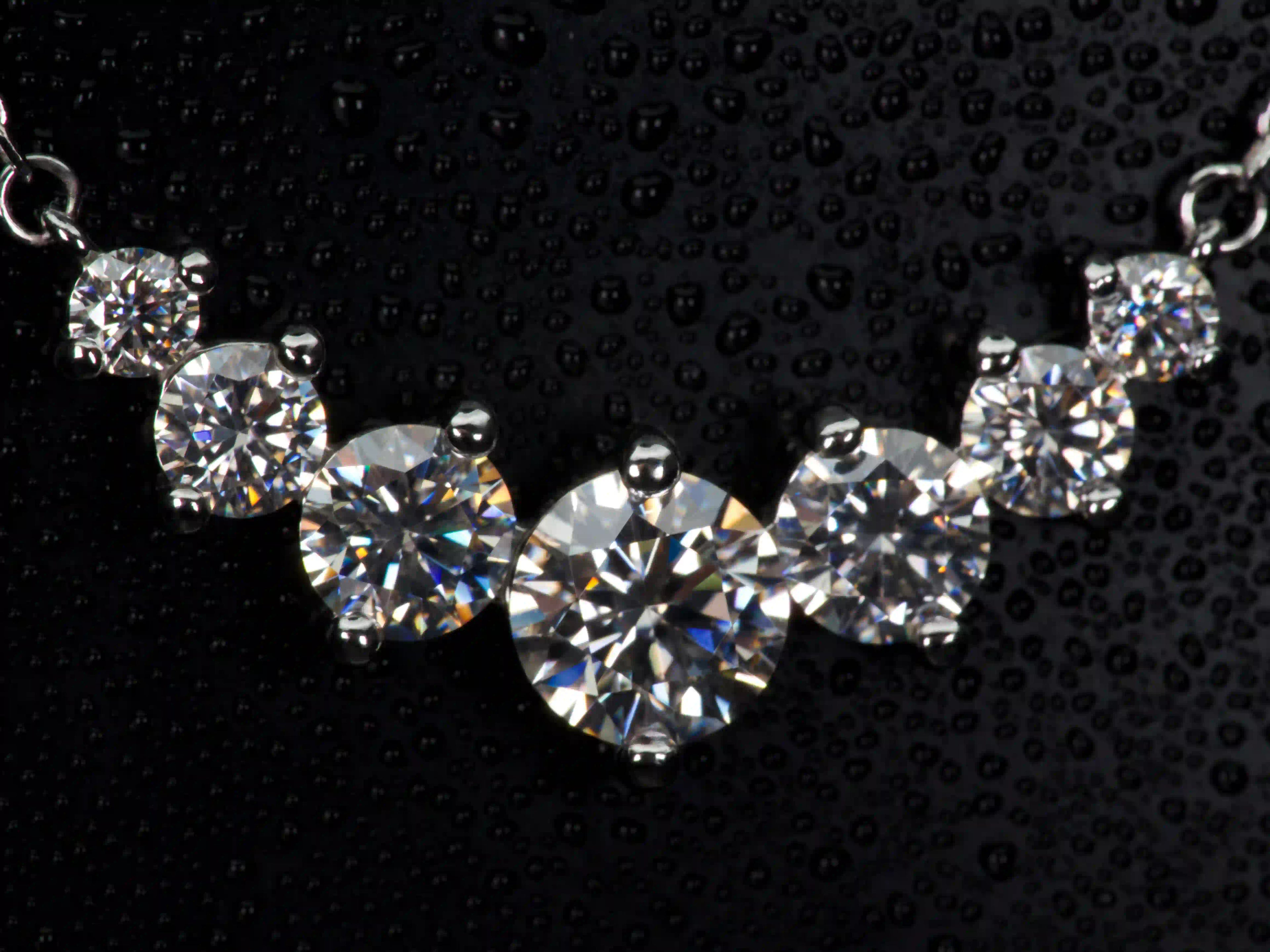 Echte Macro Fotos einer Moissanite Kette mit Größenverlauf aus 6 Steinen – zentraler großer Stein mit abgestuften kleineren Steinen, intensives Funkeln und Feuer im echten Licht, 925 Sterling Silber mit Weißgold Veredelung, auffälliger als Diamant