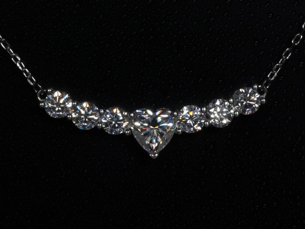 Moissanite-Kette mit Herzschliff – frontal fotografiert, zentraler Moissanite in Herzform mit sechs runden Steinen nebeneinander in gebogener Silberfassung