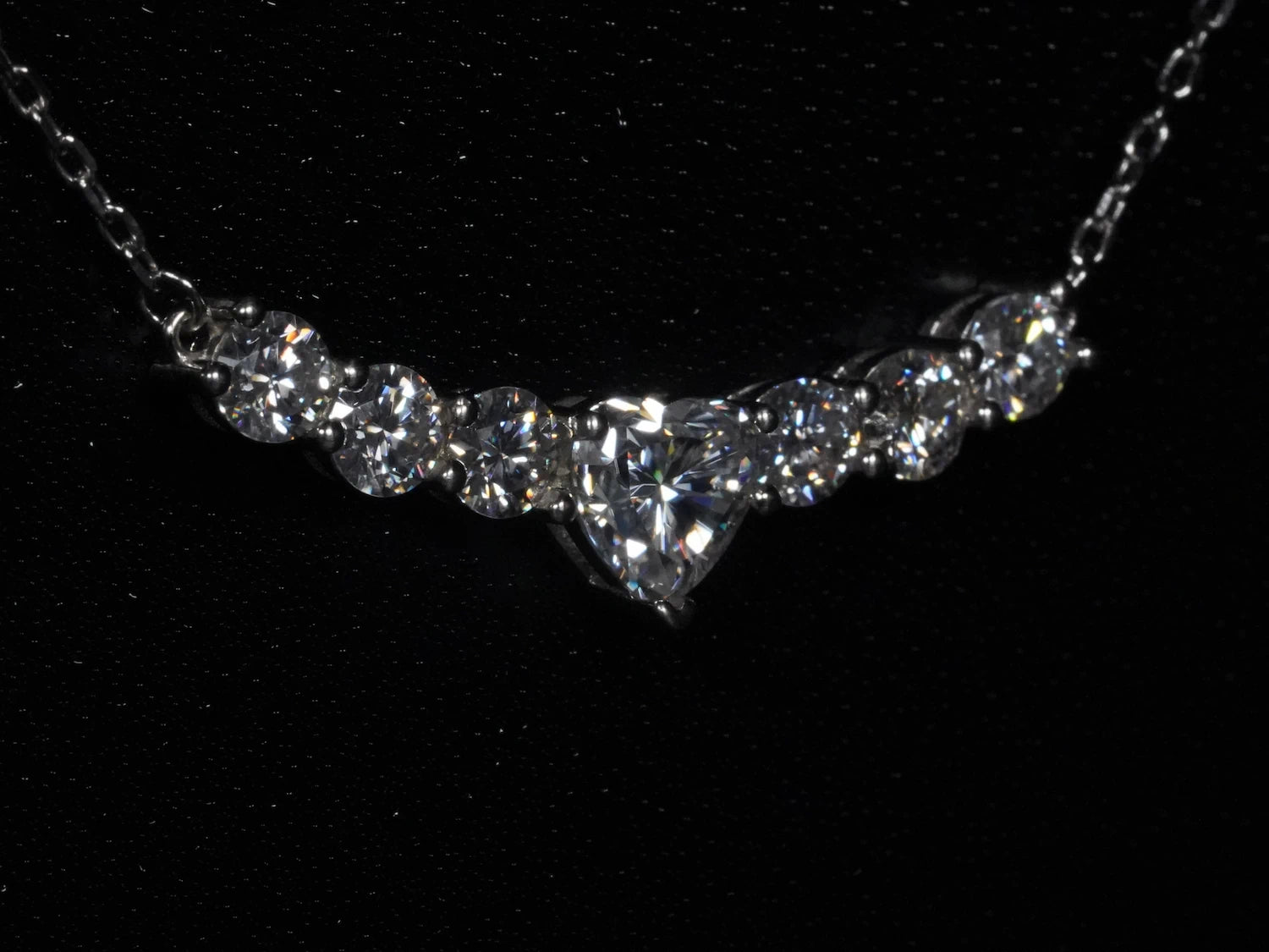 Seitliche Ansicht der Herz-Moissanite-Kette – zeigt leicht gebogene Linie aus sieben Steinen, zentrale Herzform mit runden Seitensteinen auf einer Ebene