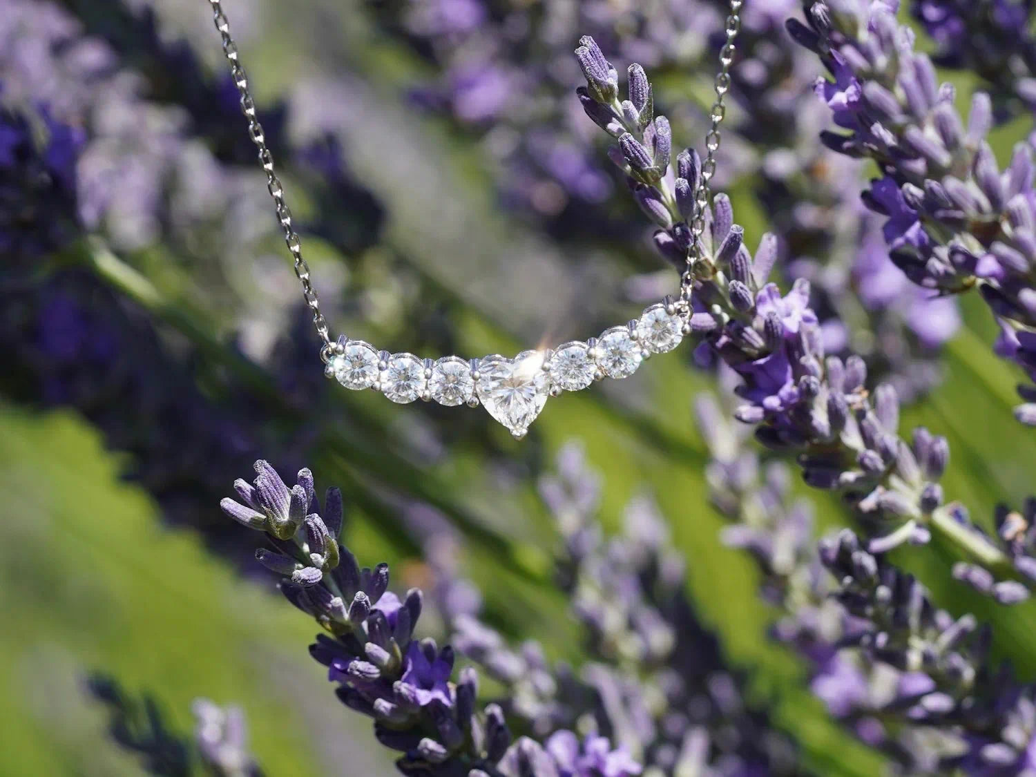 Glitzernde Moissanit-Kette mit Herz-Mittelstein und runden Steinen im Sonnenlicht