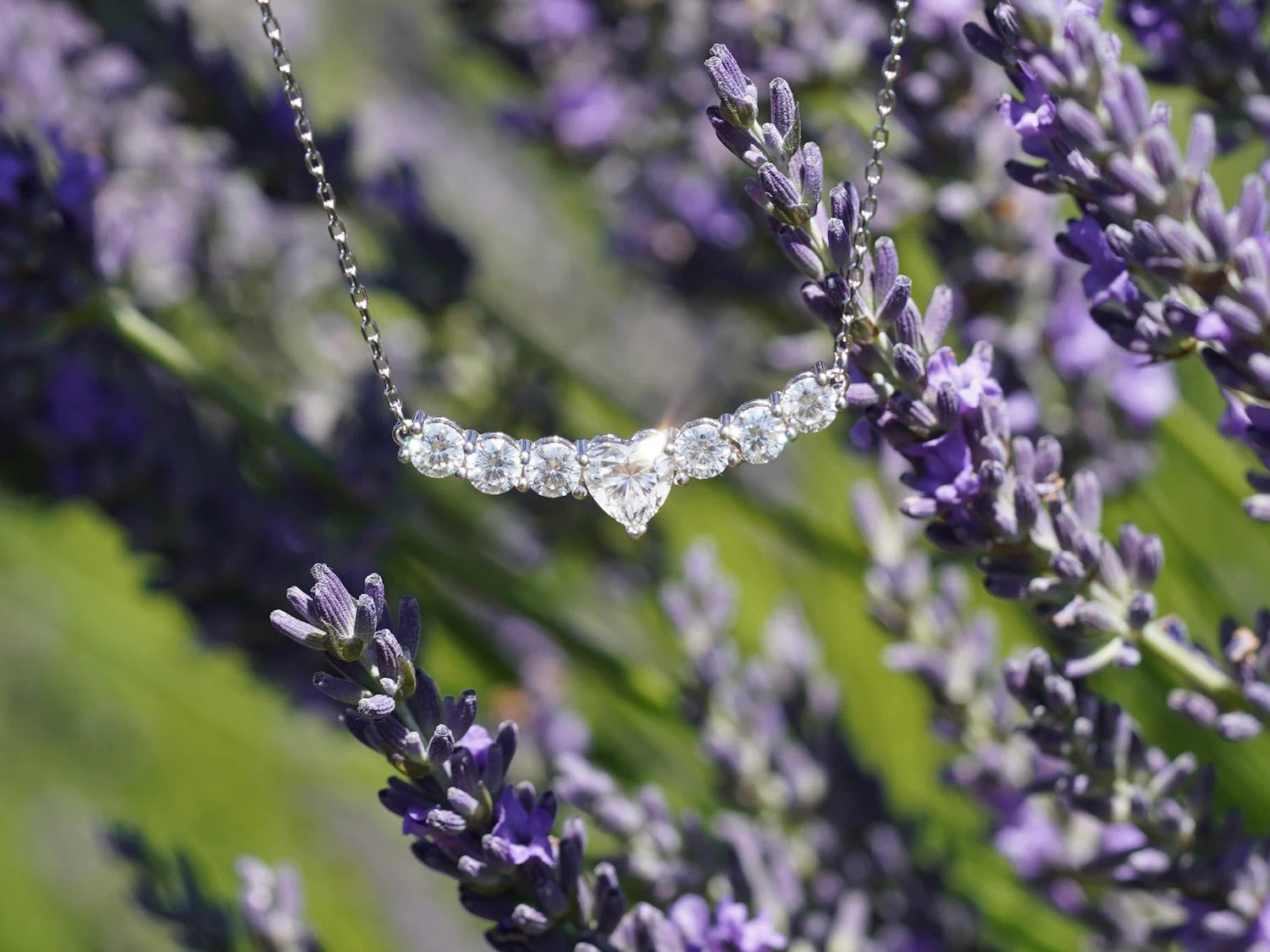 Glitzernde Moissanit-Kette mit Herz-Mittelstein und runden Steinen im Sonnenlicht
