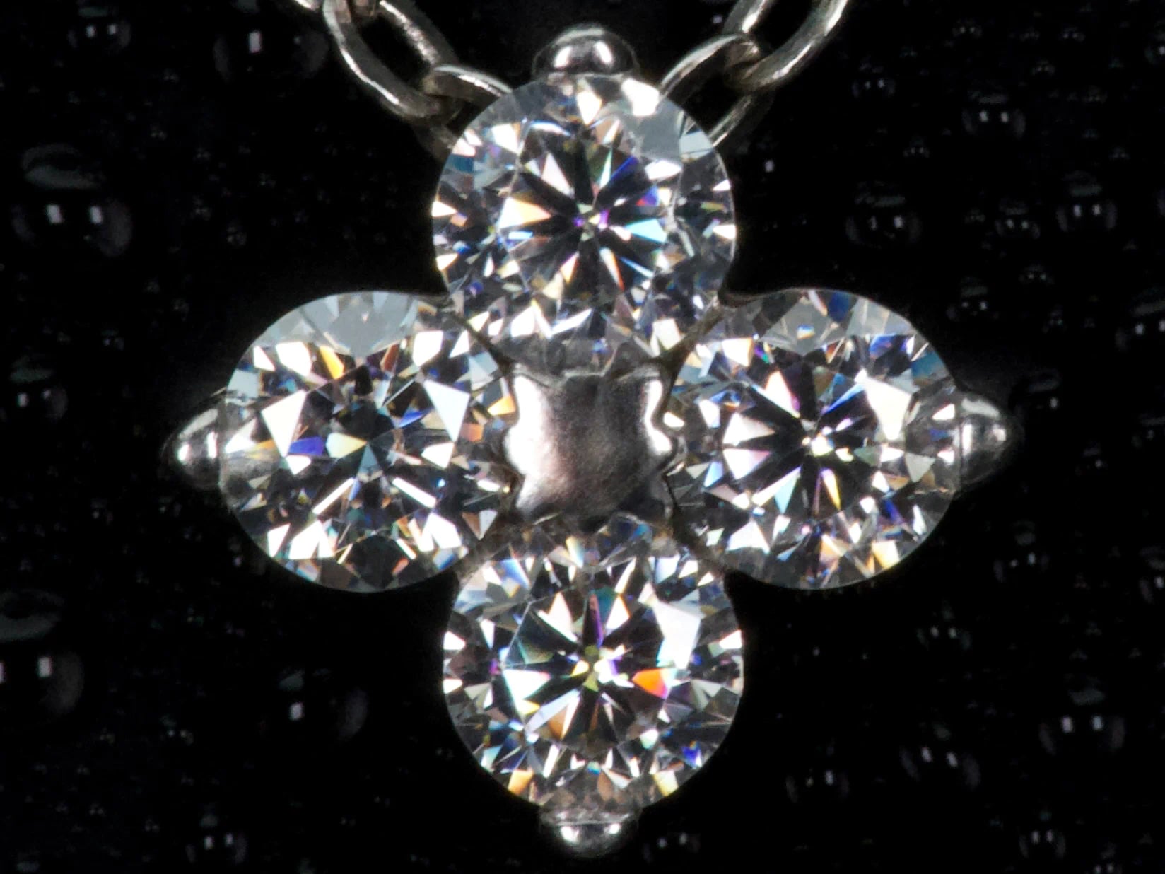 Echte Makroaufnahme einer Moissanite Kleeblatt Kette mit 0,4 ct – 4-blättriger Anhänger mit brillanten Steinen und intensivem Funkeln im Licht, gefertigt aus 925 Sterling Silber mit Weißgold Veredelung