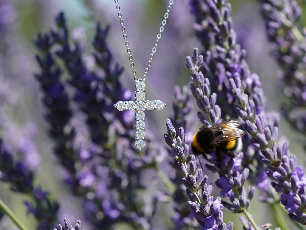 925 Sterling Silber Moissanit Kreuzanhänger vor Lavendel mit Hummel – christlicher Schmuck bei natürlichem Sonnenlicht