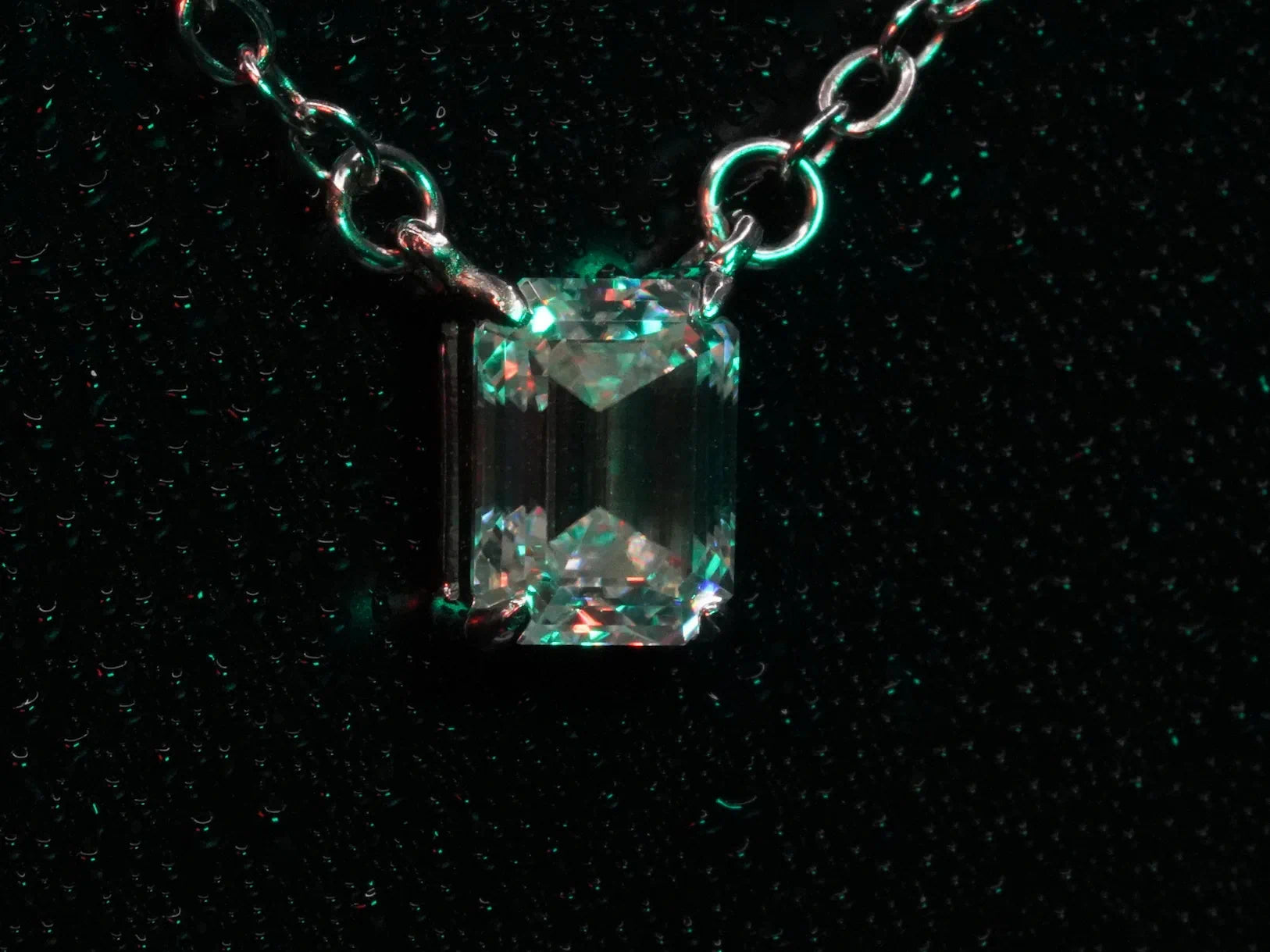 Seitliches Foto vom Moissanite Smaragd in Grünem Licht an einer Silber Kette