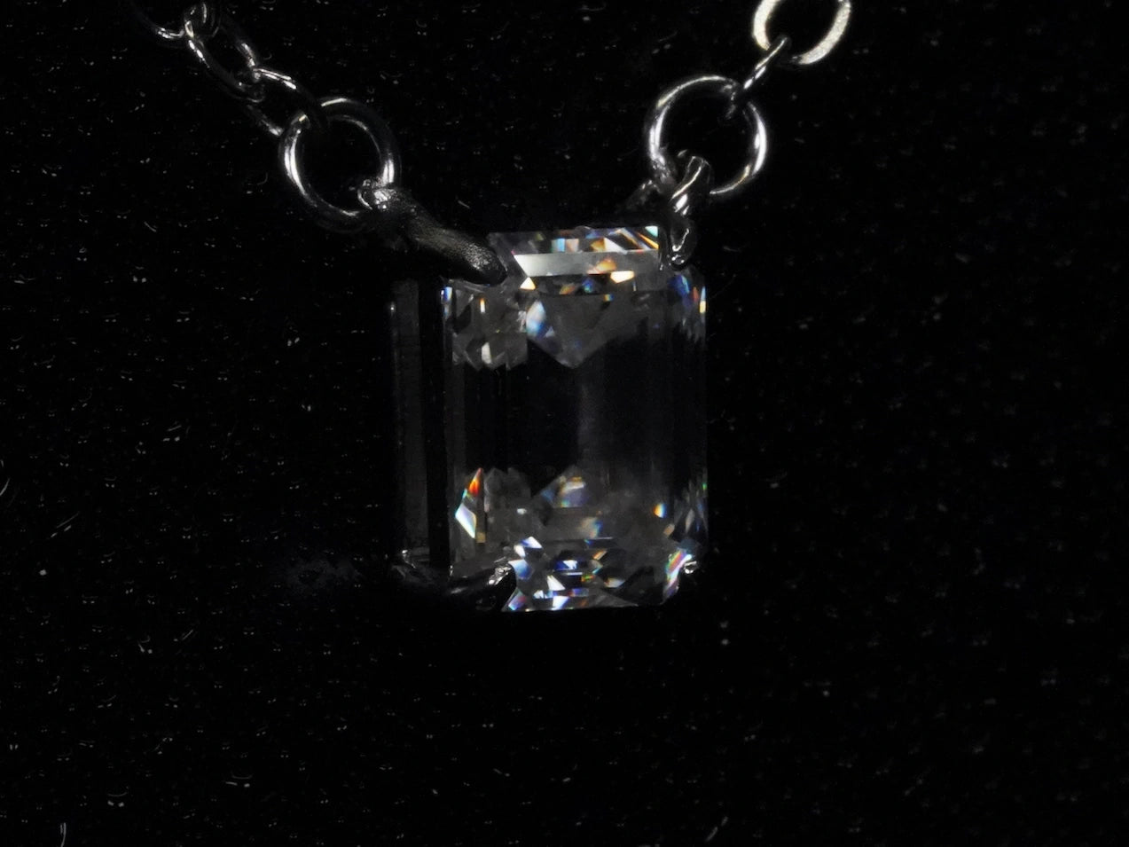 Seitliches Foto vom klaren Moissanite Smaragd Anhänger in Sterling Silber gefasst.