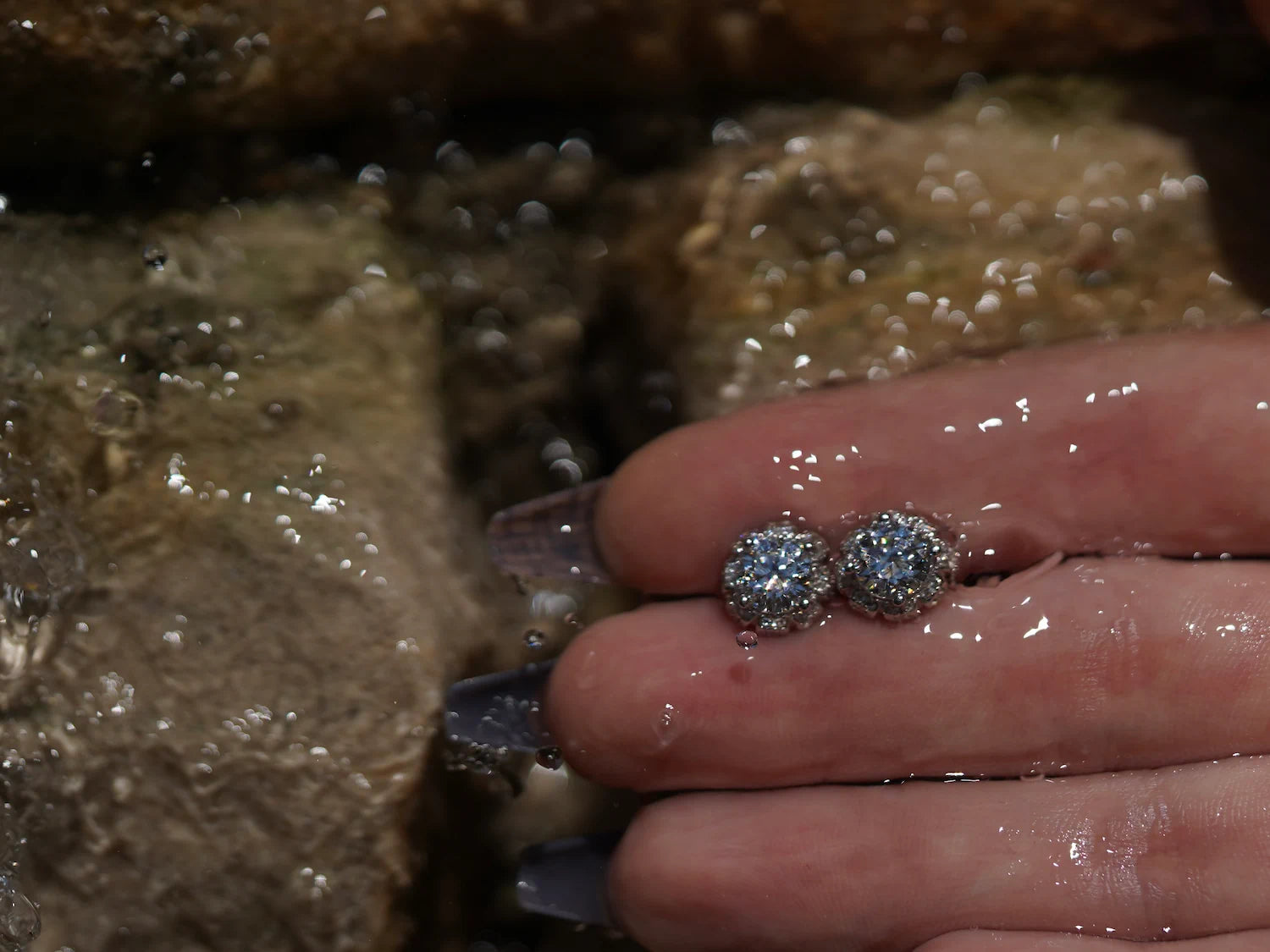 Moissanite Ohrringe mit floralem Schliff vor fließendem Wasser, facettenreicher Moissanite Schmuck aus Sterling Silber im Licht.