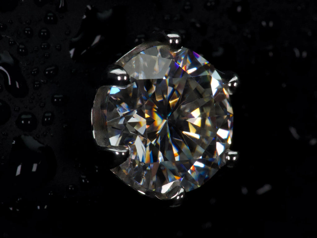 Echte Ultra Macro Aufnahme eines Moissanite Ohrsteckers mit 6 Zinken Fassung – extreme Lichtbrechung, intensives Feuer und sichtbare Facettenstruktur, deutlich stärkeres Funkeln als Diamant im direkten Vergleich