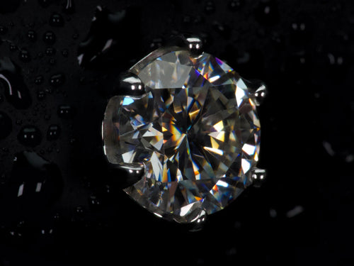 Echte Ultra Macro Aufnahme eines Moissanite Ohrsteckers mit 6 Zinken Fassung – extreme Lichtbrechung, intensives Feuer und sichtbare Facettenstruktur, deutlich stärkeres Funkeln als Diamant im direkten Vergleich