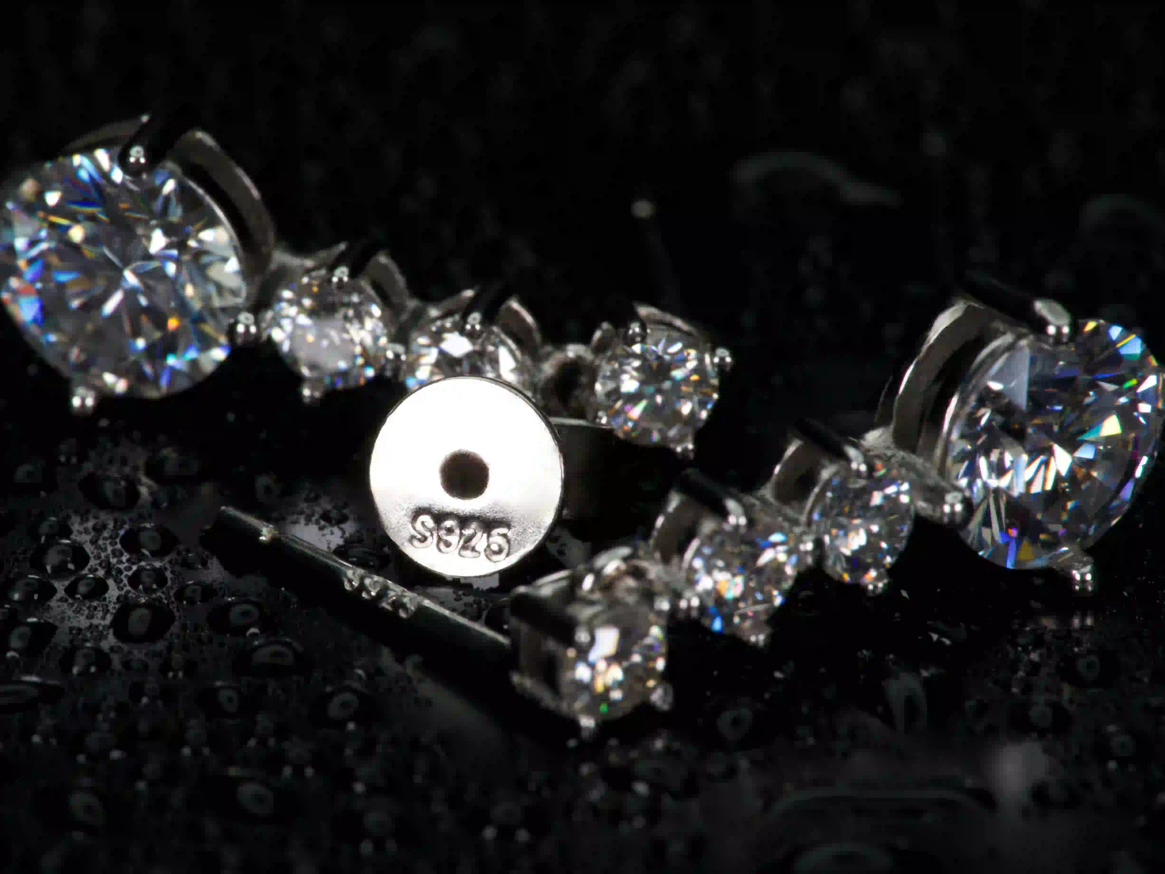 925 Silber Stempel und Butterflyverschluss der Moissanite Ohrstecker, im Hintergrund unscharf funkelnde Steine im echten Licht, hochwertige Verarbeitung sichtbar
