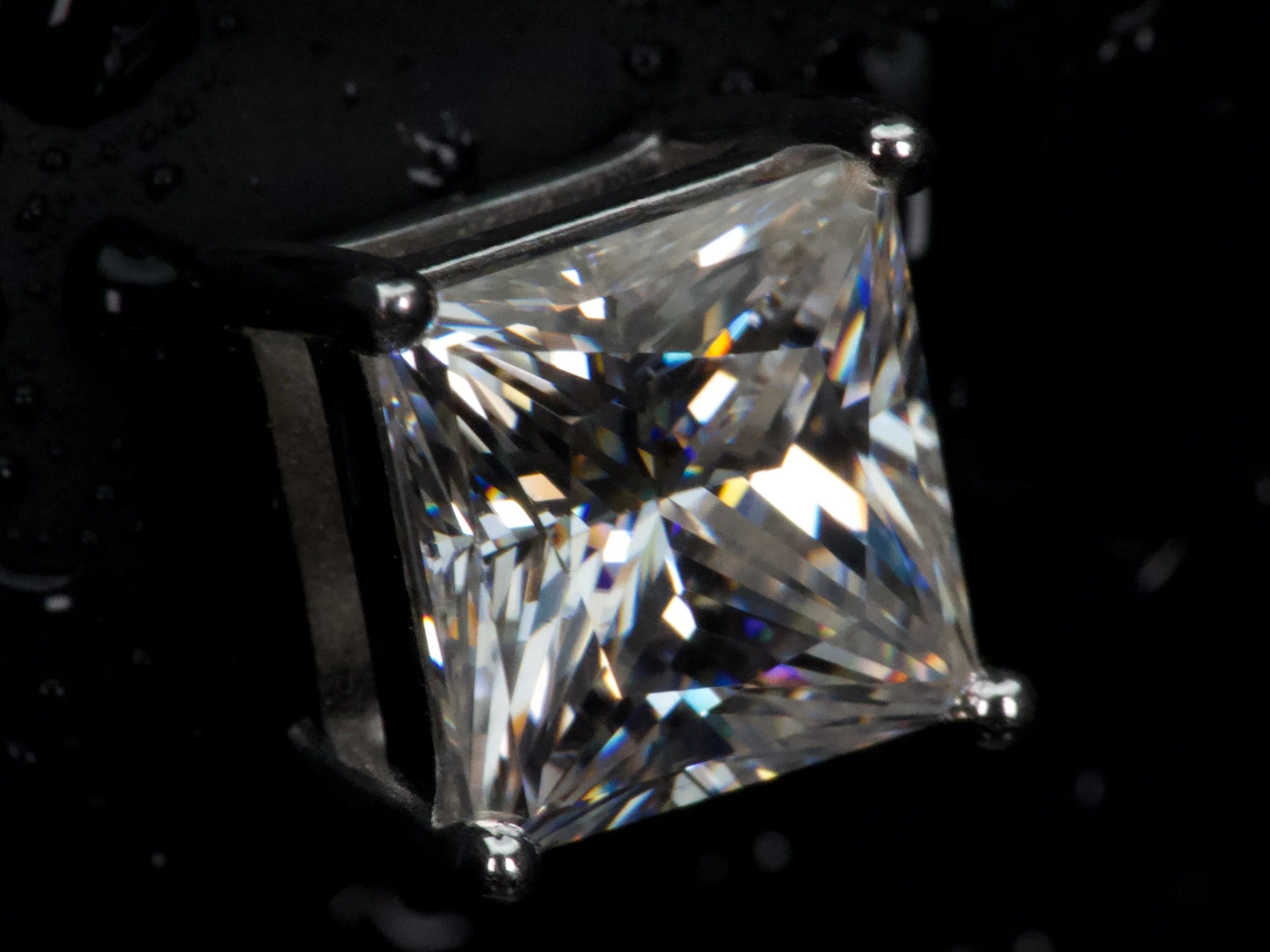 Echte Ultra-Makroaufnahme eines Moissanite Ohrsteckers im Princess Cut – extrem klare Facetten und scharfe Kanten mit starkem Funkeln und Feuer im Licht, 925 Sterling Silber