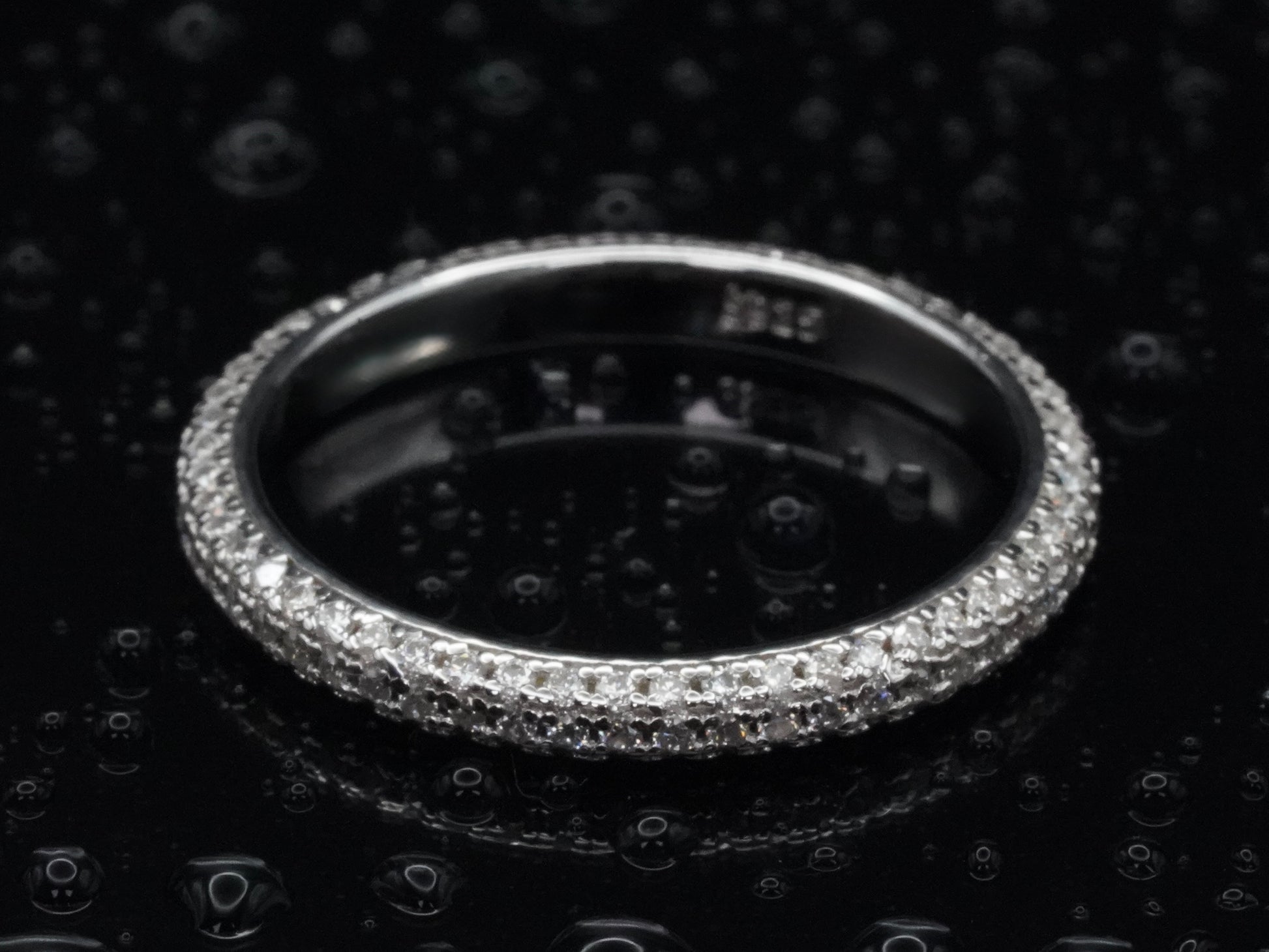 Draufsicht auf den Moissanite Pavé-Ring mit 1 mm kleinen Steinen – symmetrisch gesetzte Brillantschliffe in durchgehender Silberfassung