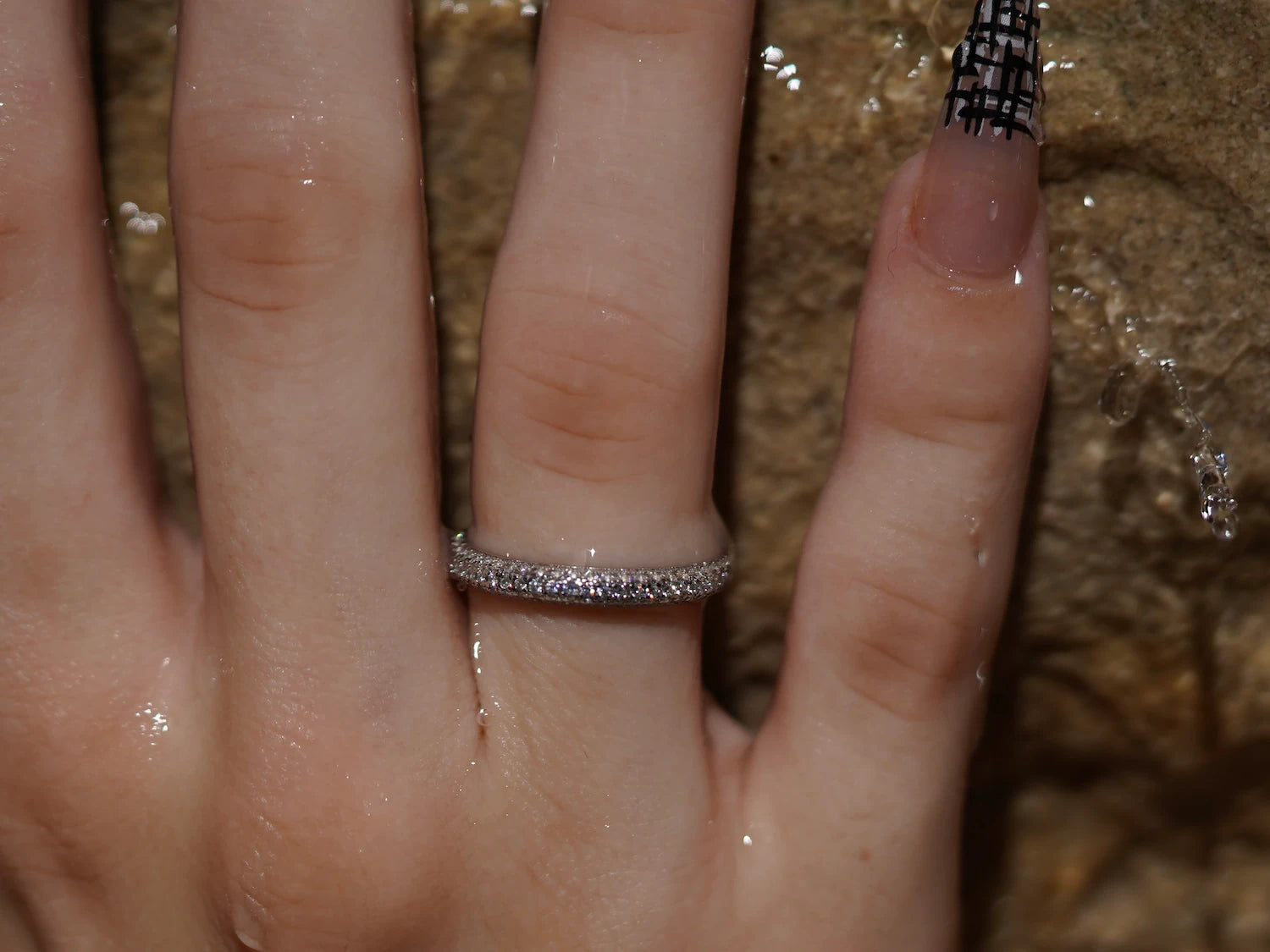 Moissanite Ring vor fließendem Wasser, dezenter Moissanite Schmuck aus Sterling Silber mit Weißgold, fein geschliffene Steine im Licht.