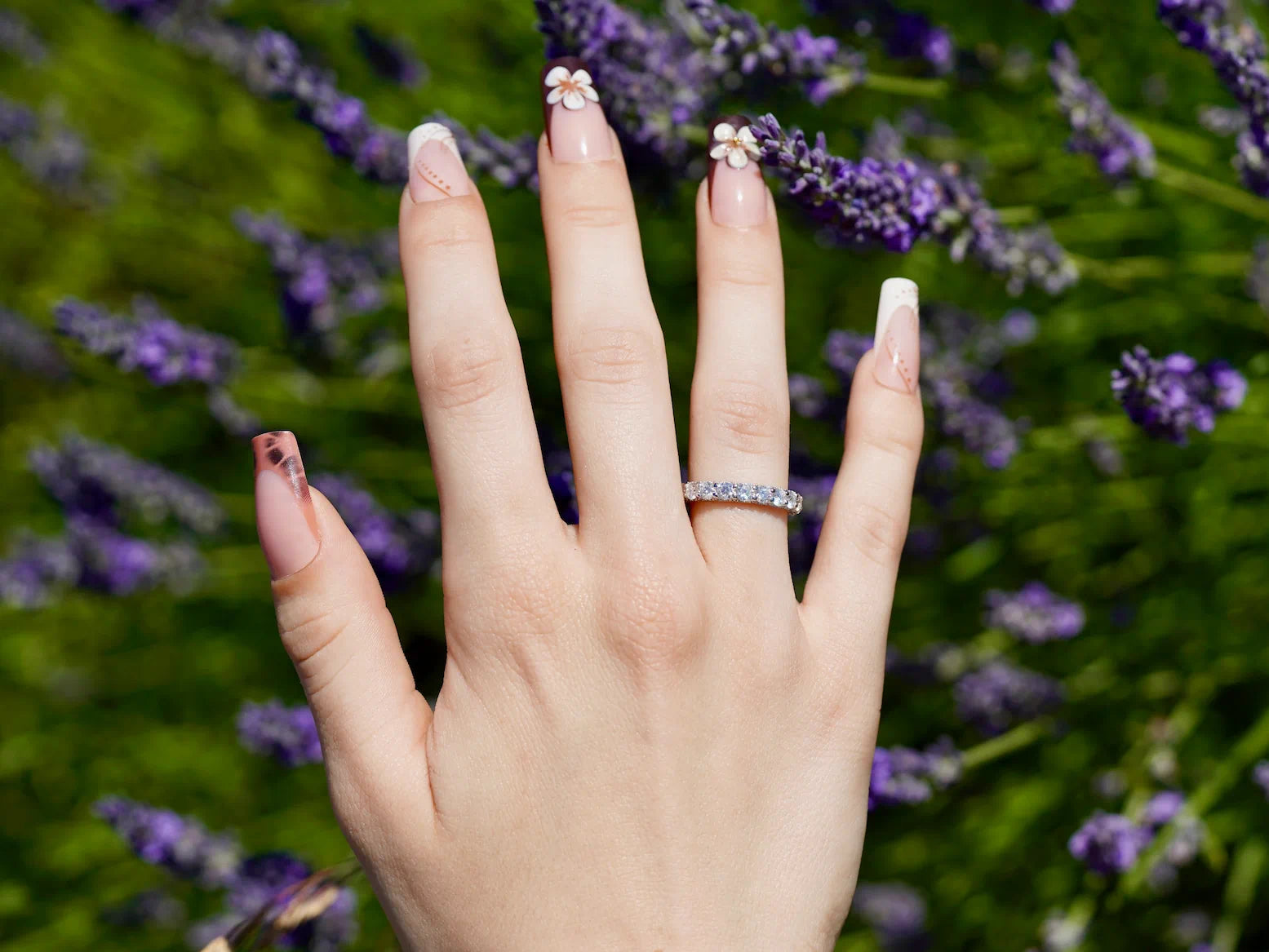 Glitzernder Statement-Ring aus Moissanit und Silber mit 18k Weißgold mit Nebensteinen mit Lavendel im Hintergrund