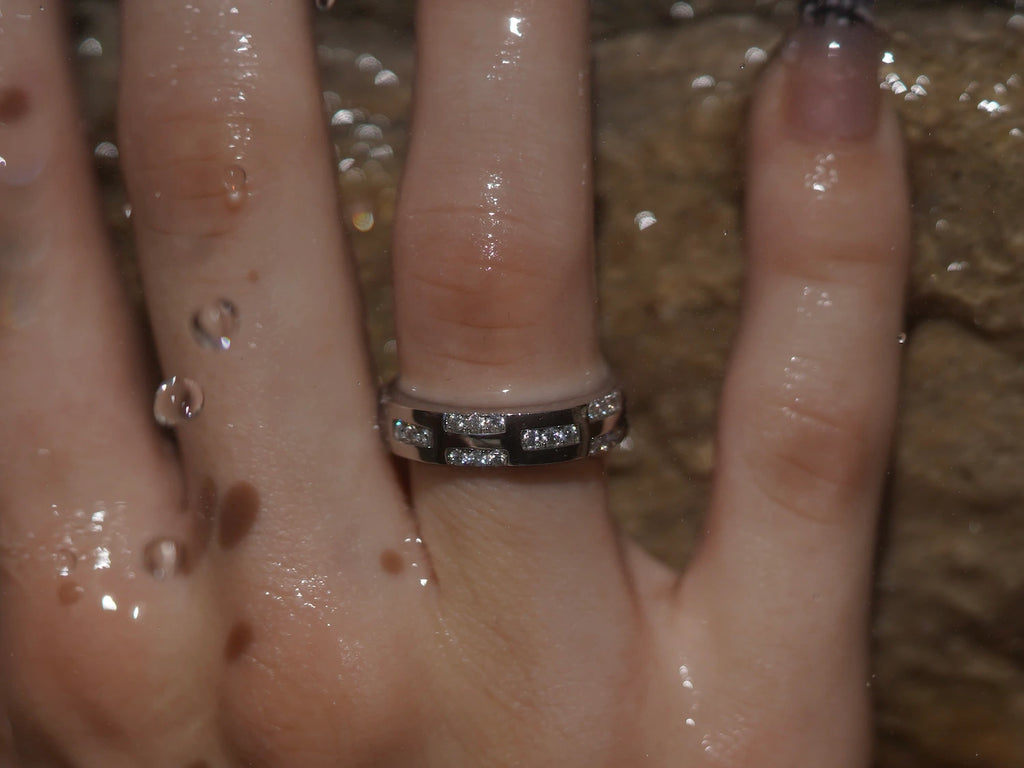 Moissanit Eternity-Ring mit 5 mm Steinen vor Sandsteinwand – kraftvoller Moissanite Ring aus Sterling Silber mit Weißgold, durchgehendes Funkeln und luxuriöse Präsenz.