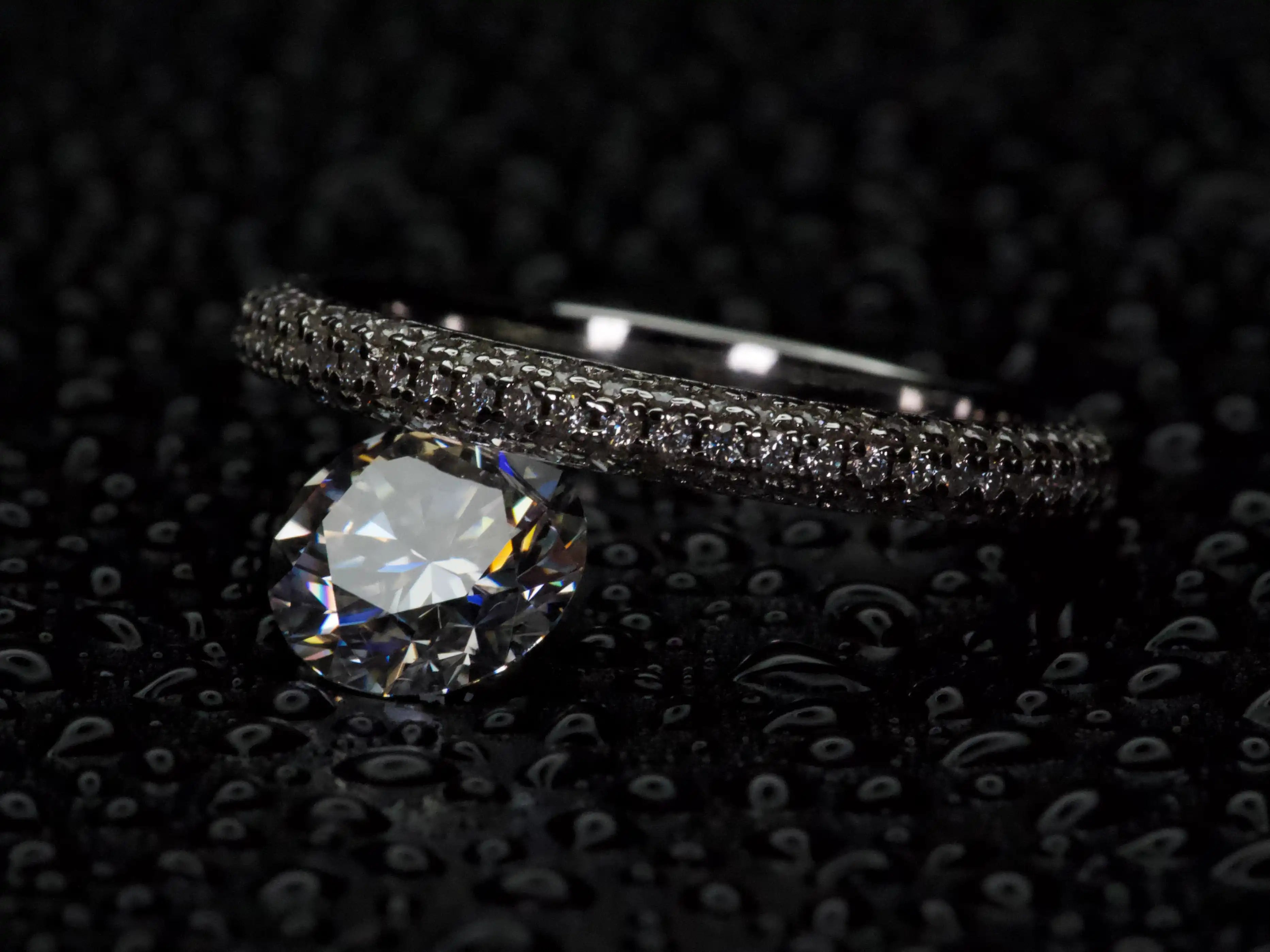 Moissanite Pavé Ring balanciert auf einem 2ct Stein – extreme Makroaufnahme mit starkem Funkeln und realistischen Lichtreflexen