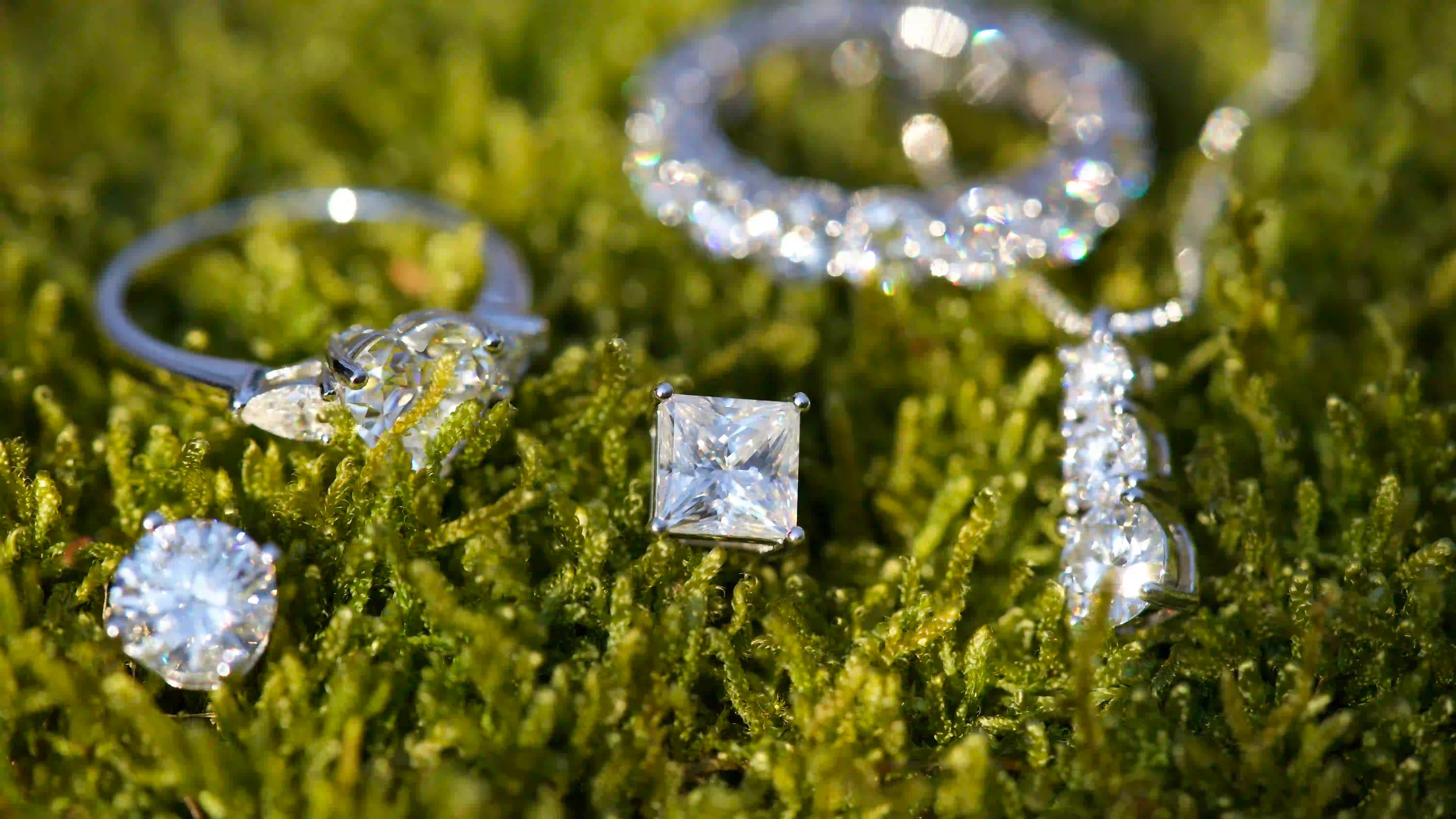 moissanite schmuck set mit ring ohrring und halskette im makro foto auf grünem moos mit funkelnden steinen und natürlichem licht
