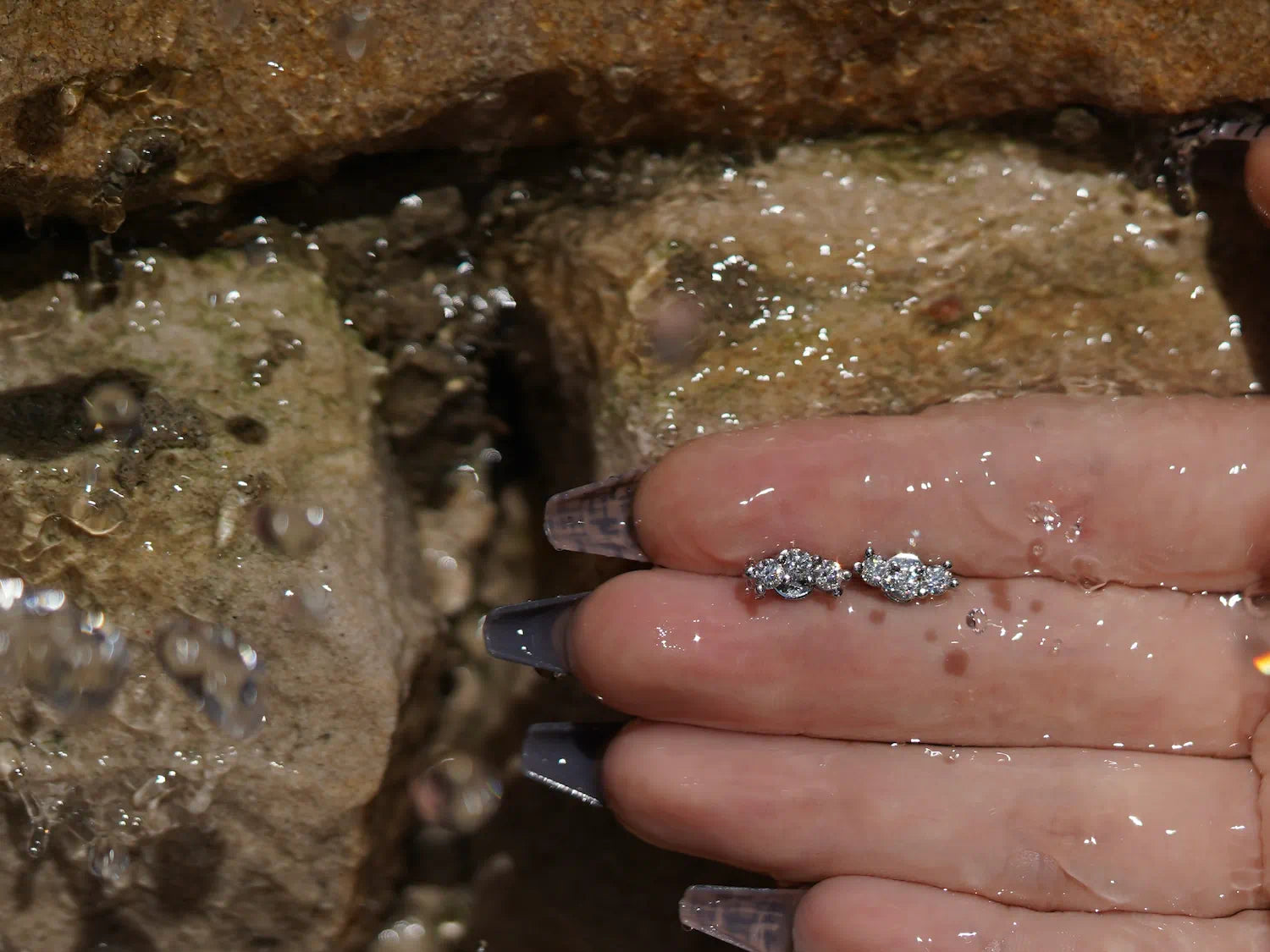 Moderne Moissanite Ohrstecker vor Sandsteinwand – dreifach gefasst, aus Sterling Silber mit Weißgold, minimalistisches Design mit brillanter Wirkung.