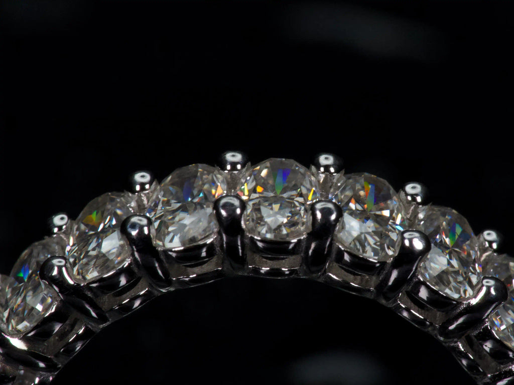 Ultra Makroaufnahme eines ovalen Moissanite Eternity Rings aus 925 Silber & Weißgold. Sichtbare Facetten, starke Lichtreflexe und intensives Funkeln im echten Licht. Echte Produktfotografie mit präziser Krappenfassung und stärkerem Funkeln als bei Diamanten.