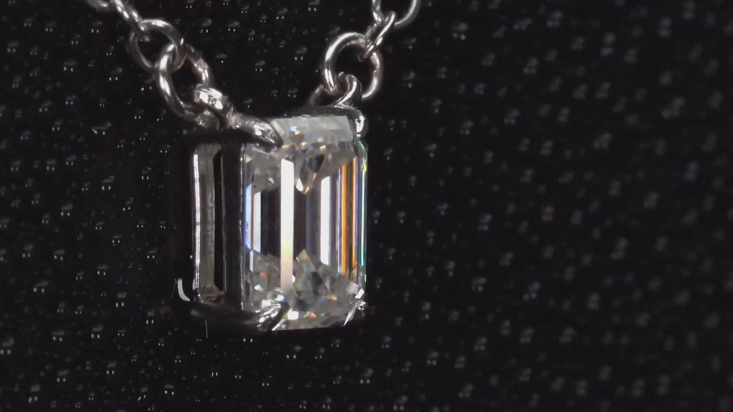 Echte Macro Videoaufnahme einer Moissanite Kette mit 2ct Smaragdschliff Anhänger – rechteckiger Emerald Cut zeigt klares, tiefes Funkeln im Licht, gefasst in 925 Sterling Silber mit 18K Weißgold Veredelung