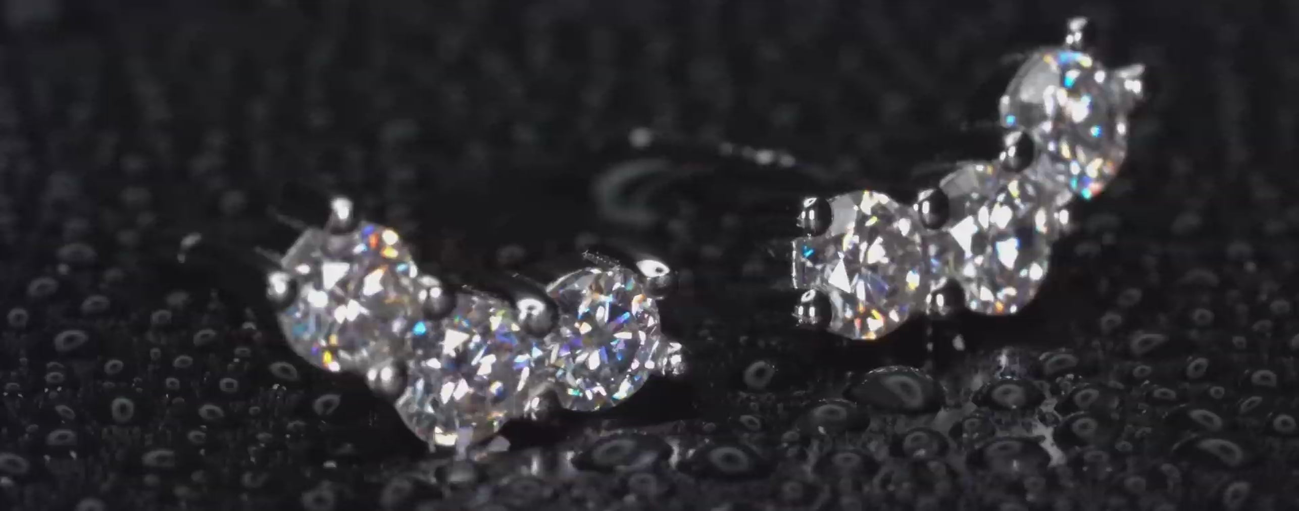 Echte Videoaufnahme von Moissanite Ohrsteckern mit 3 Steinen in Klammerform im echten Licht. Intensives IRL Funkeln mit starken Lichtreflexen und diamantähnlicher Brillanz bei jeder Bewegung. 925 Silber & 18K Weißgold Ohrstecker mit luxuriösem Glanz für Alltag und besondere Momente.